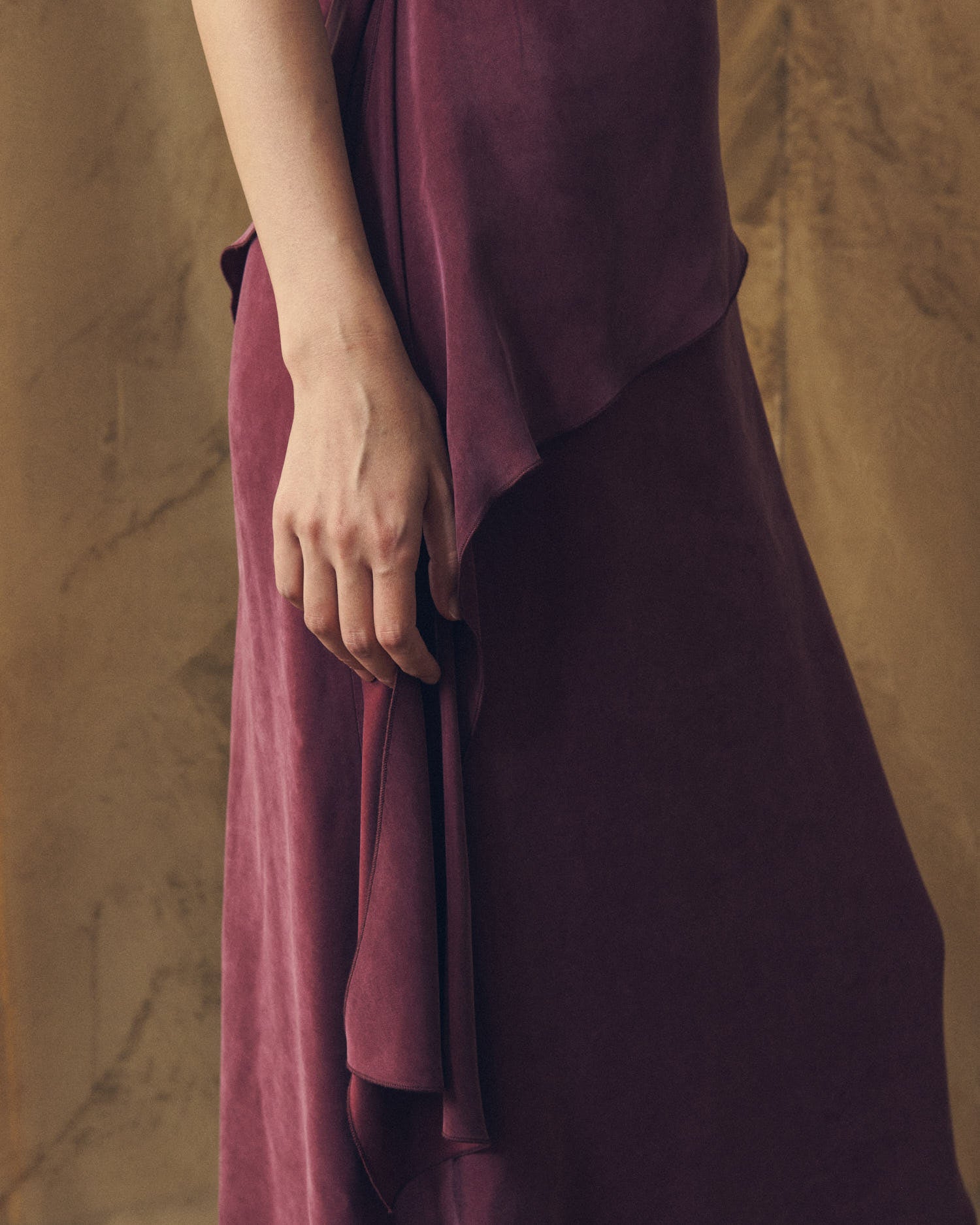 Close-up detail shot of the side ruffle drape and fabric texture on the Alina burgundy cupro dress by T.ba