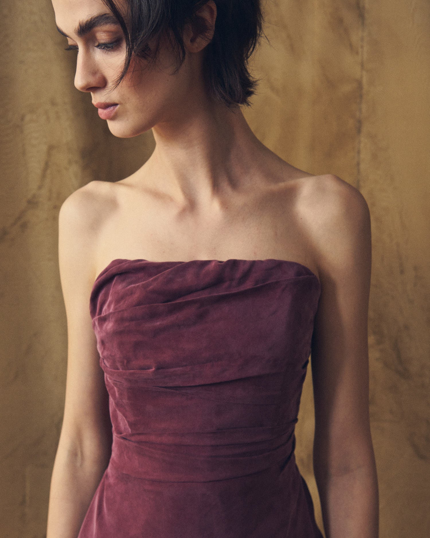 Close-up shot of the strapless pleated bodice on the Alina cupro evening dress in burgundy by T.ba