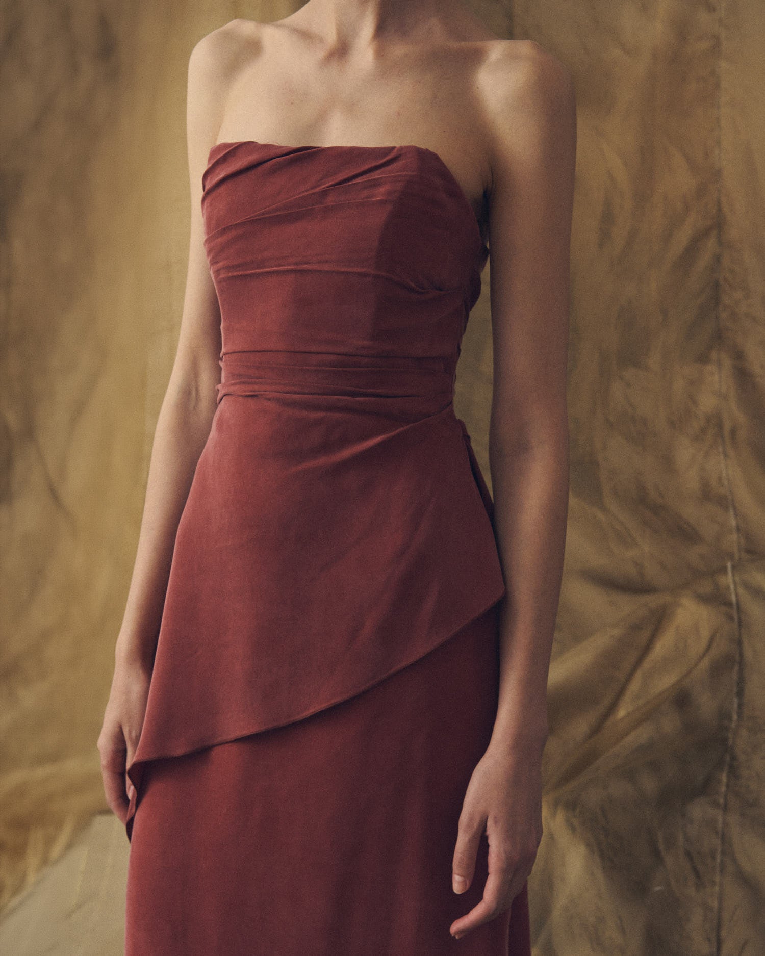 Medium shot front view of the strapless Alina cupro dress in copper highlighting pleated bodice detailing by T.ba