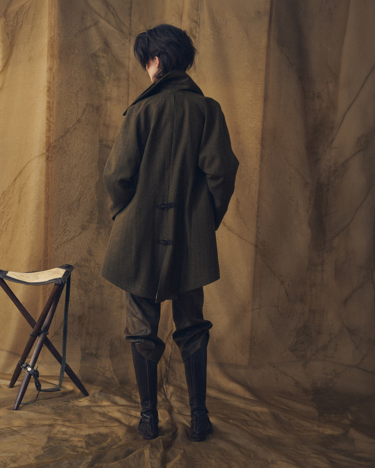 Back view of model wearing black leather knee-high boots with side buckles and wool coat for women T.ba