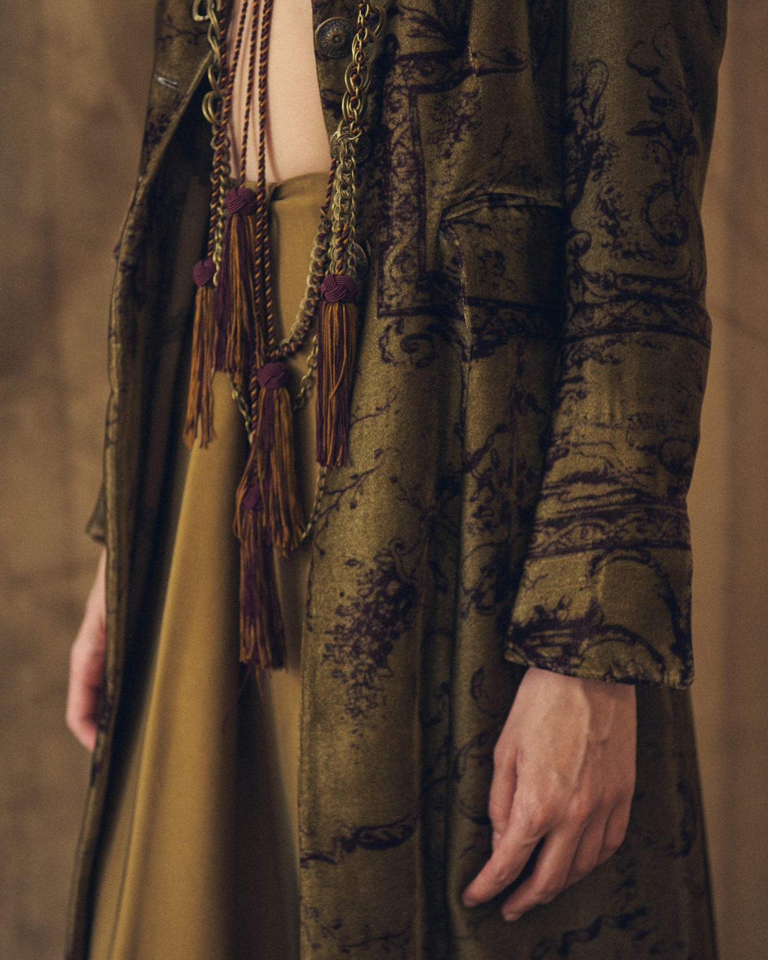 Medium shot front view showing the Baltea Borgogna metal chain belt with burgundy and ochre hanging tassels by T.ba