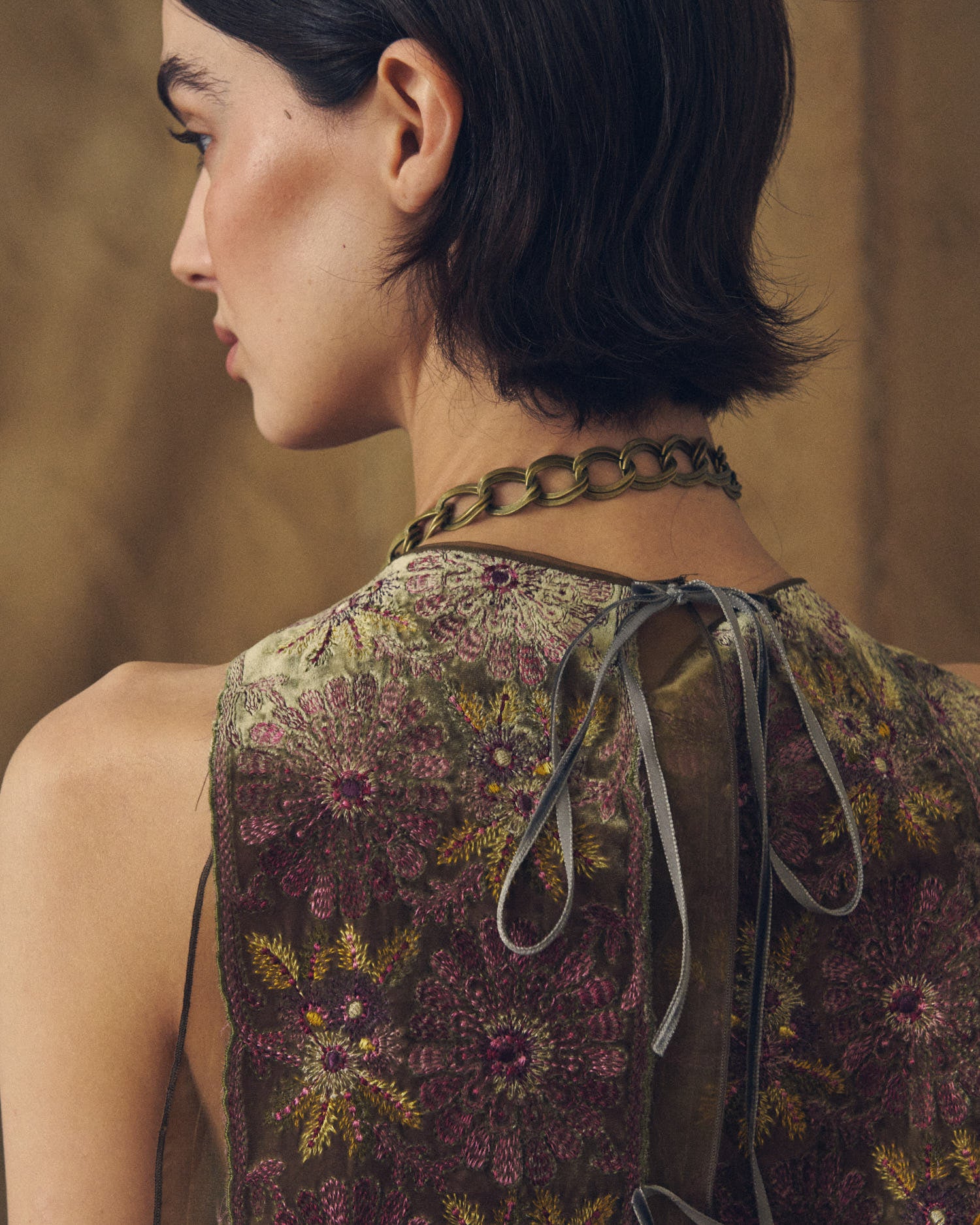 Back profile view of model highlighting the Baltea Borgogna metal link chain wrapped around the neck by T.ba