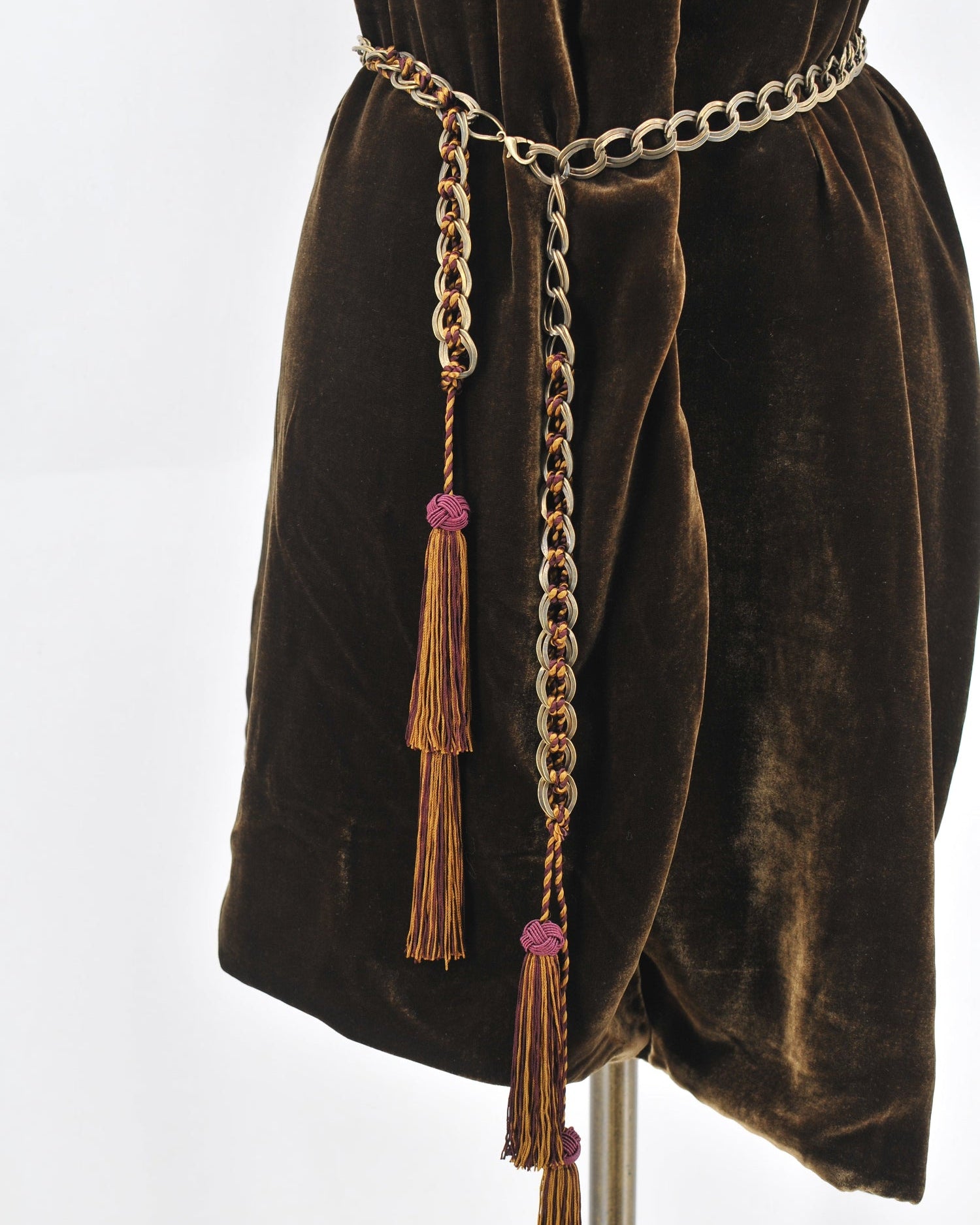 Studio product shot of the Baltea Borgogna metal link belt with burgundy woven cord and tassel drop on velvet dress by T.ba
