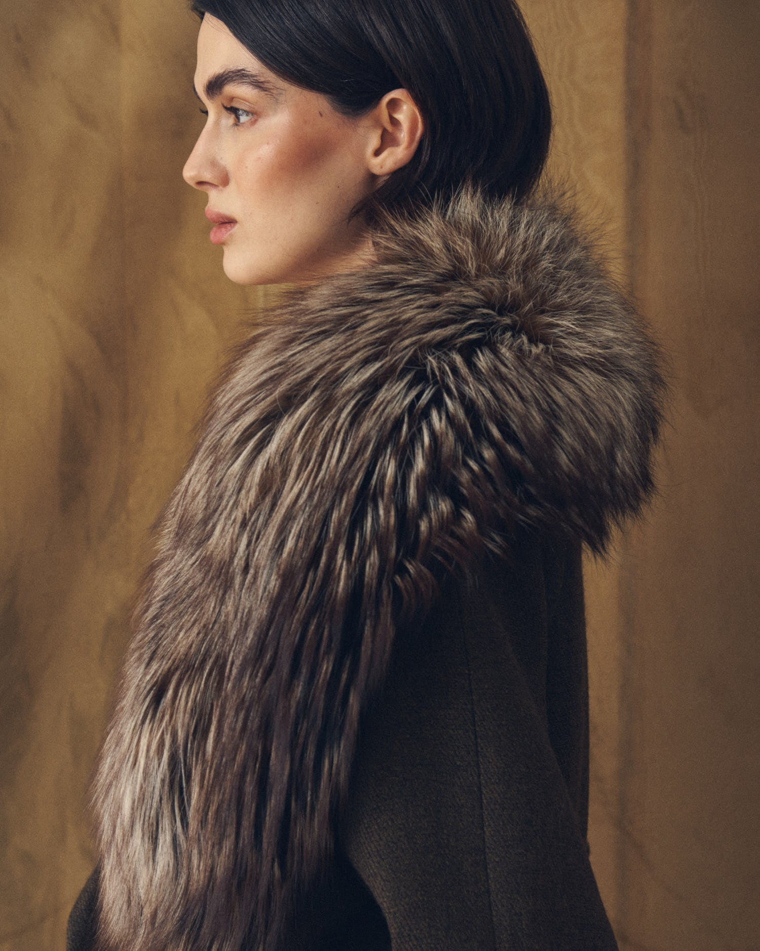 Side profile studio shot highlighting the drape of Baltea faux fur collar over shoulder by T.ba