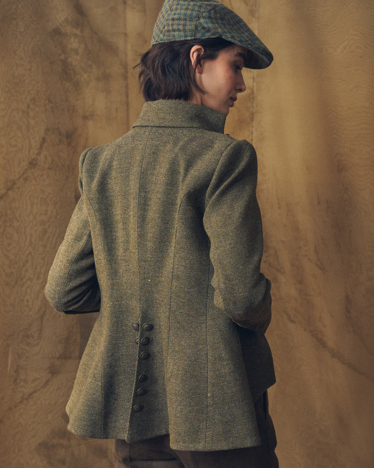 Back view of model wearing the tailored Baltea Tweed jacket showing back button detailing by T.ba
