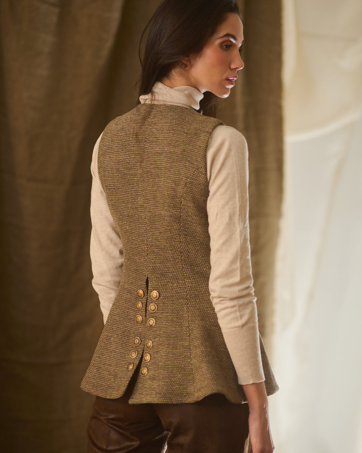 Detailed back shot showing back vent, flared hemline and gold buttons on taupe tweed Baltea vest T.ba