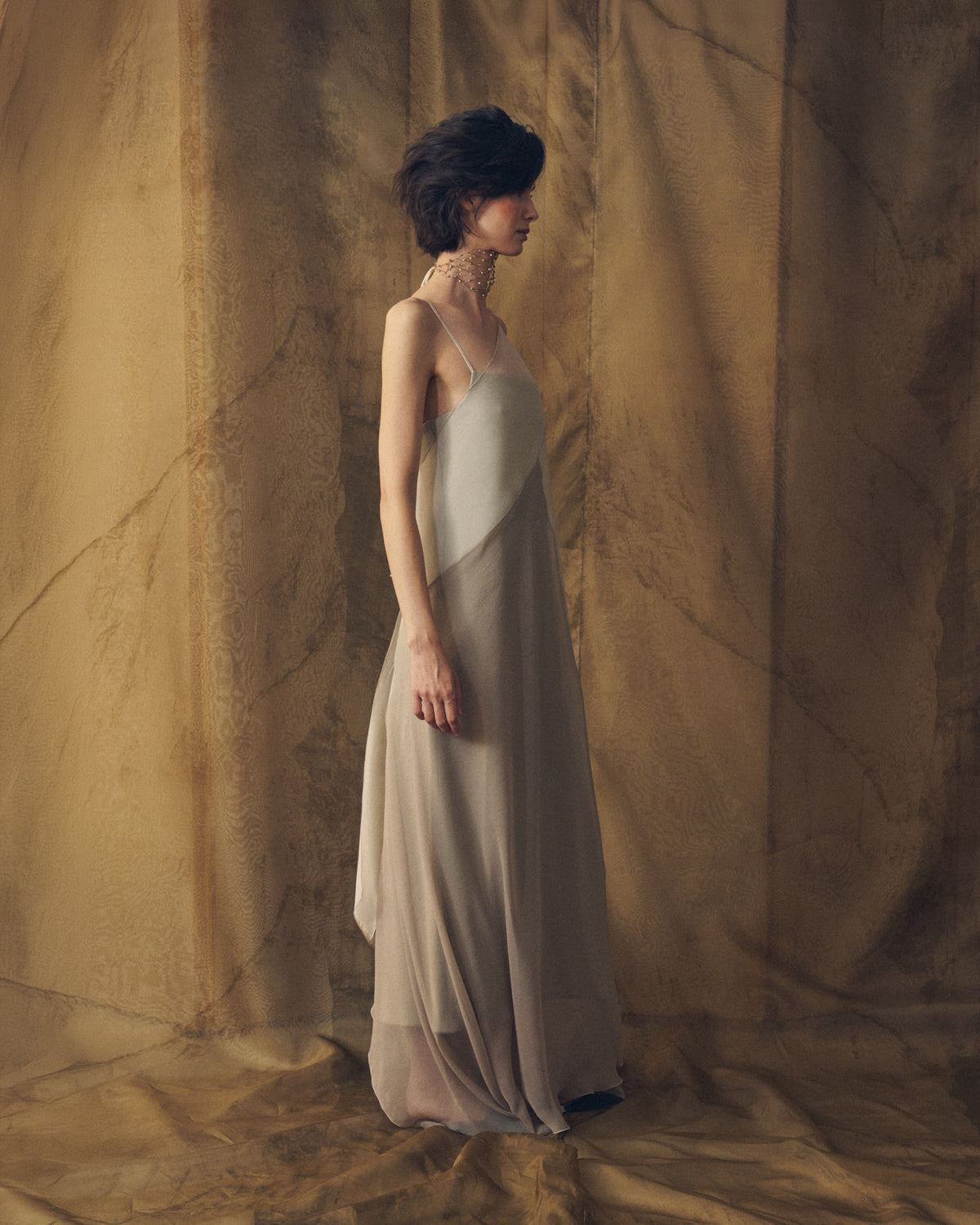 Side profile view of Biella fluid long organza dress in gray for women by T.ba