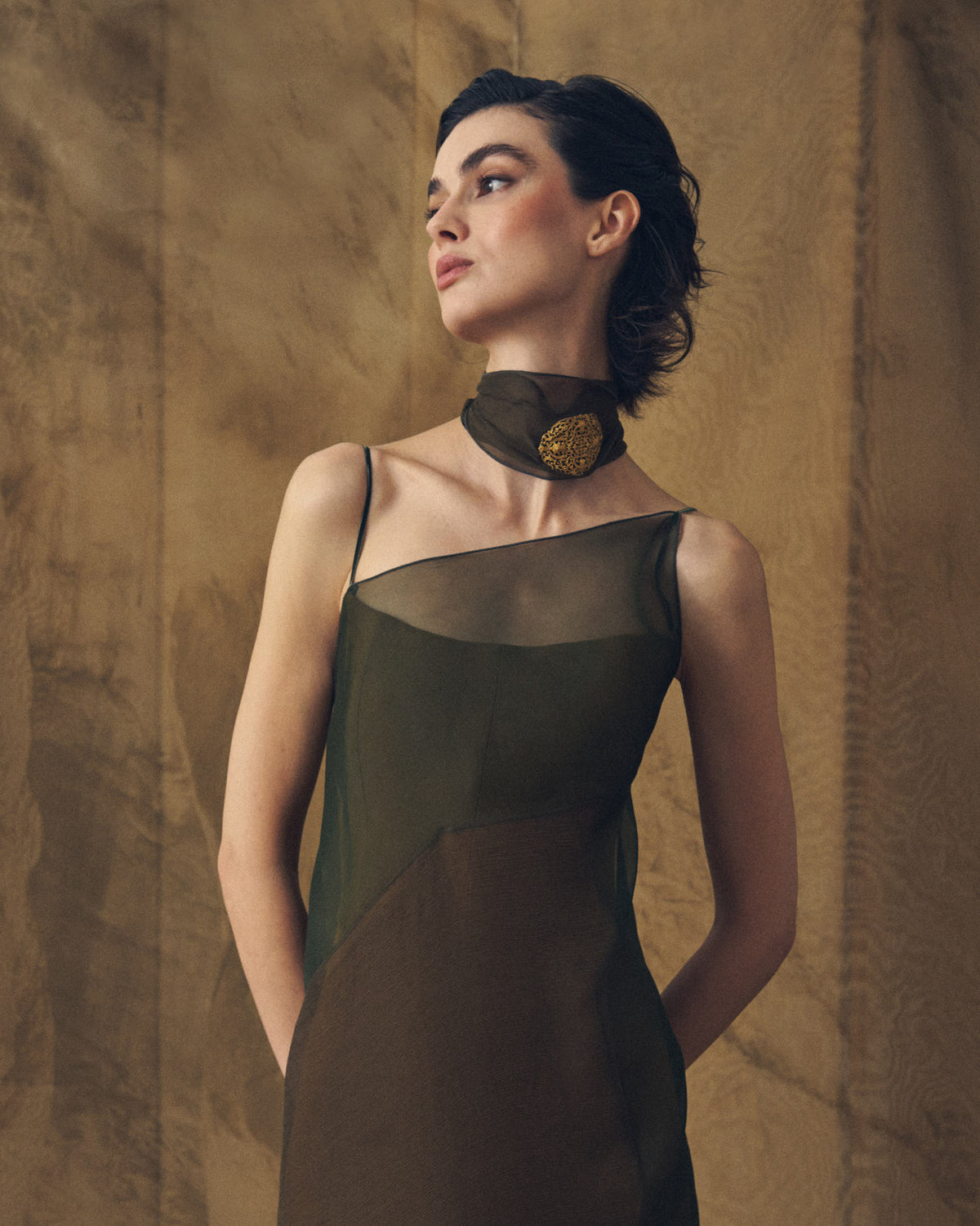Upper body front view of model wearing the Biella dress featuring the sheer asymmetrical organza overlay in hunting green by T.ba