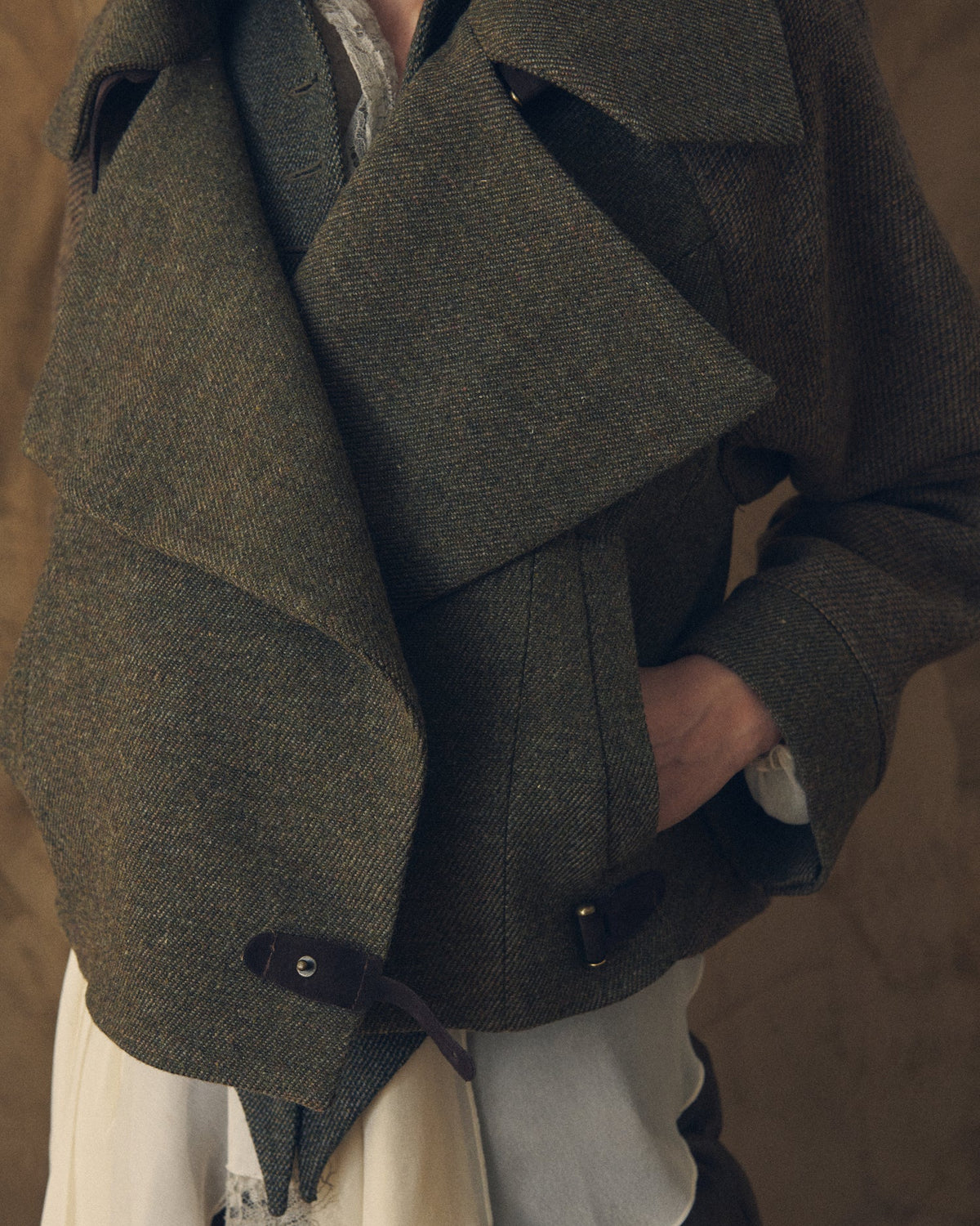 Close-up of the crossed lapels, herringbone tweed texture, and leather strap details on the Biella bomber jacket for women T.ba