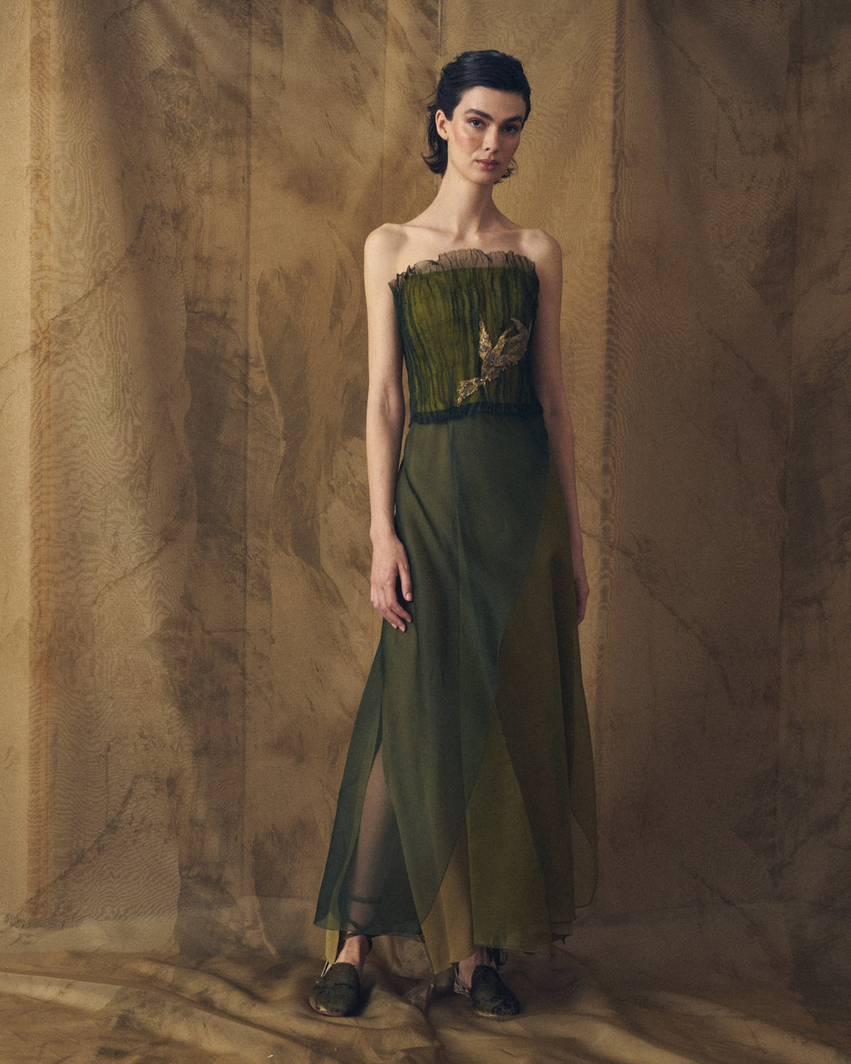 Full-length front studio view of model wearing the strapless Birdie top in hunting green pleated organza with gold embroidery by T.ba