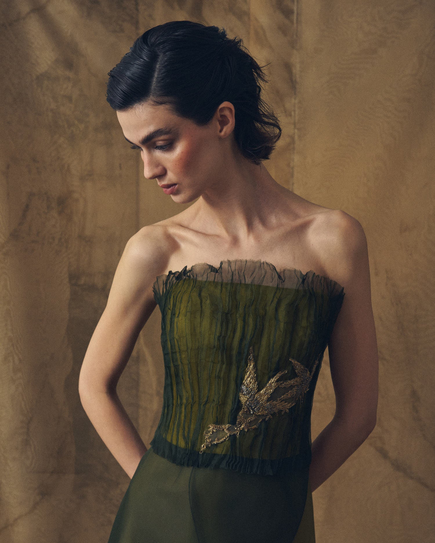 Close-up shot of the pleated bodice texture and bird embroidery on the strapless Birdie top in hunting green by T.ba