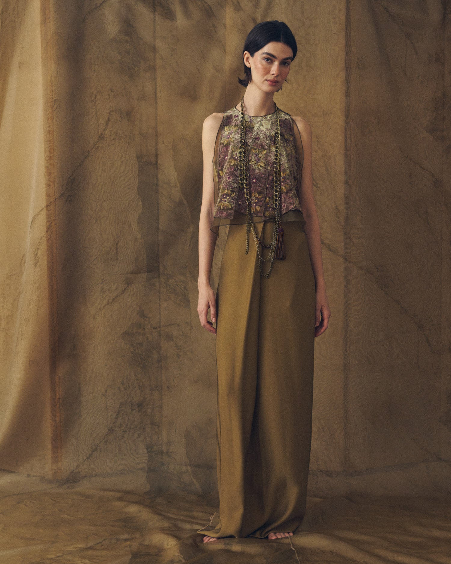 Full length shot of model wearing the Carlo sleeveless top in floral embroidered green and aubergine velvet with high waist trousers by T.ba