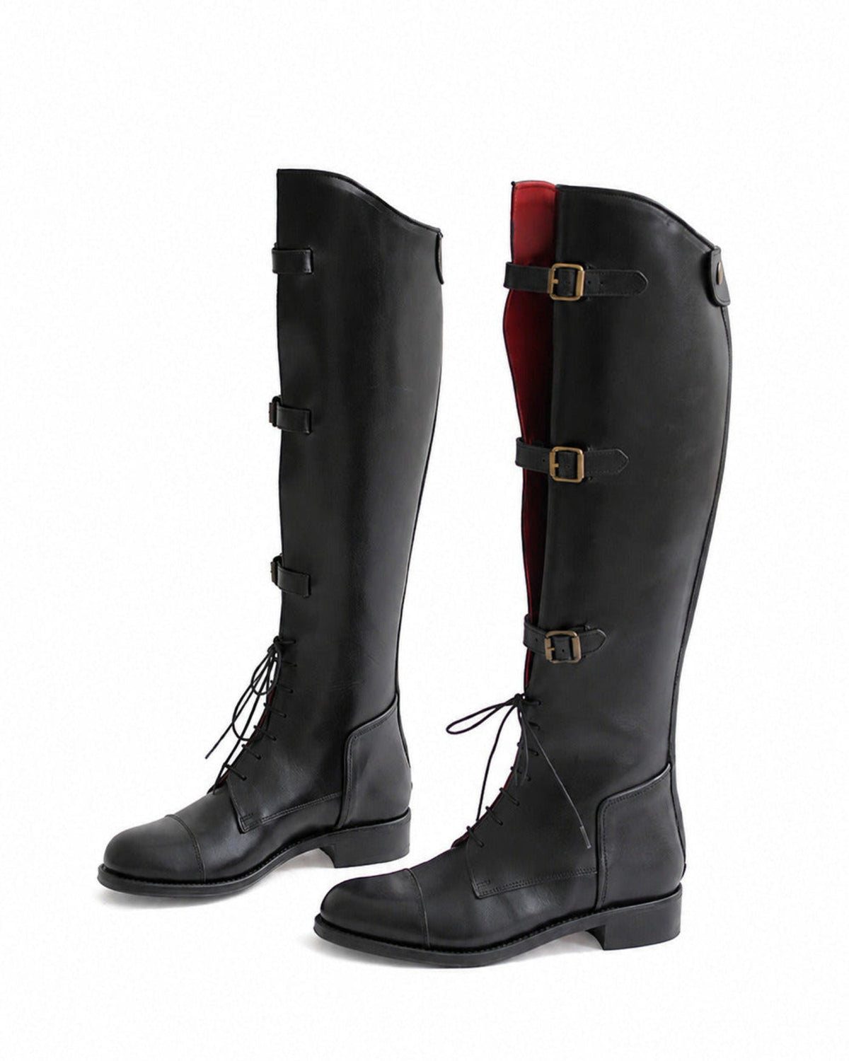 Perspective view of black leather straps riding boots showing side buckles and red lining detail T.ba