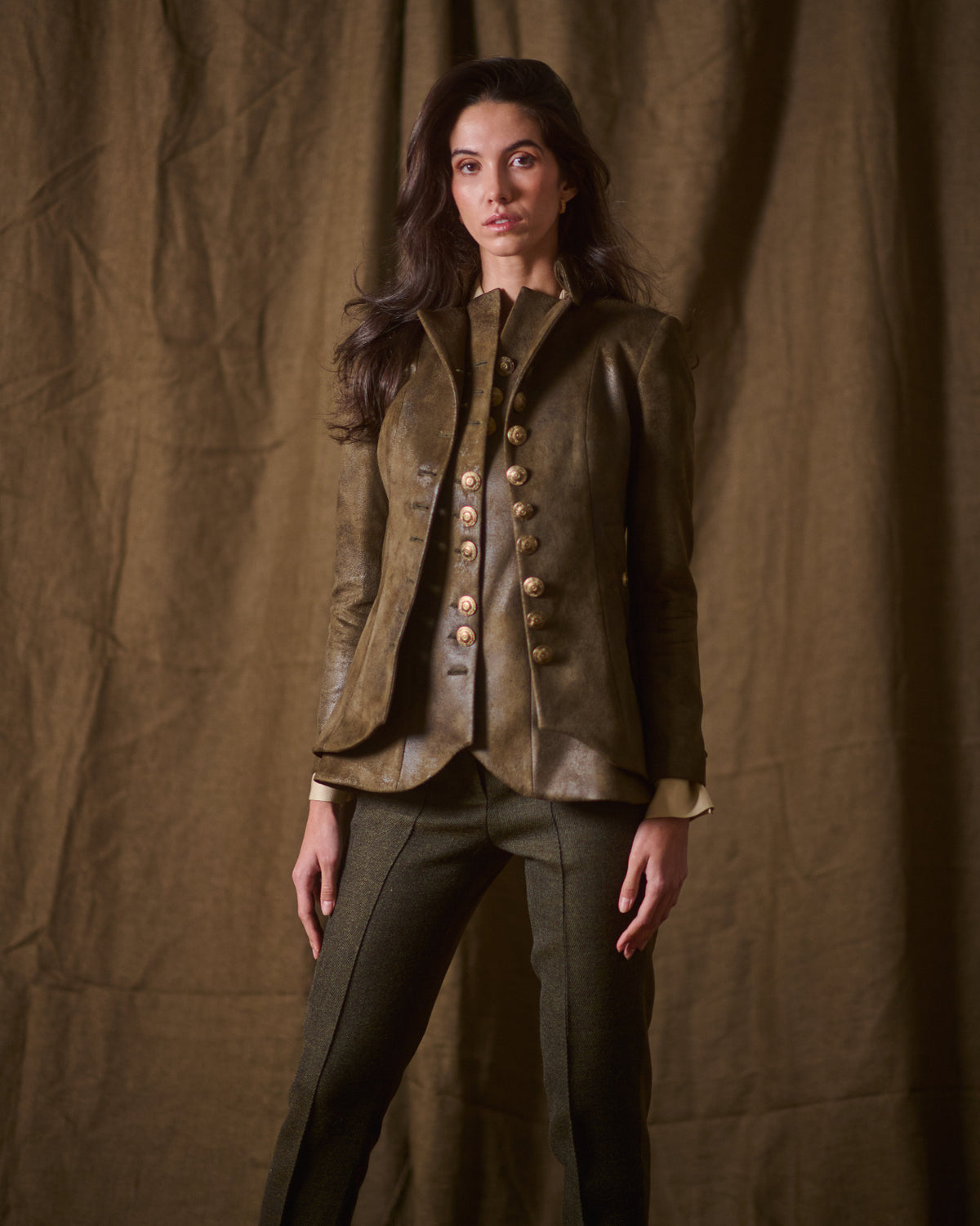 Frontal view of model wearing structured khaki leather Gnu Baltea jacket layered over matching vest for women T.ba