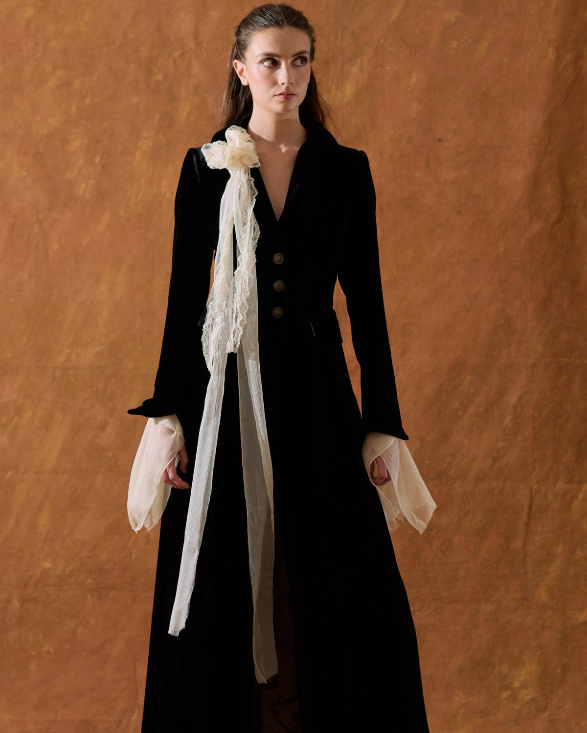 Front full-length view of model wearing the tailored Classic Coat in black silk velvet featuring a cream floral scarf detail for women by T.ba