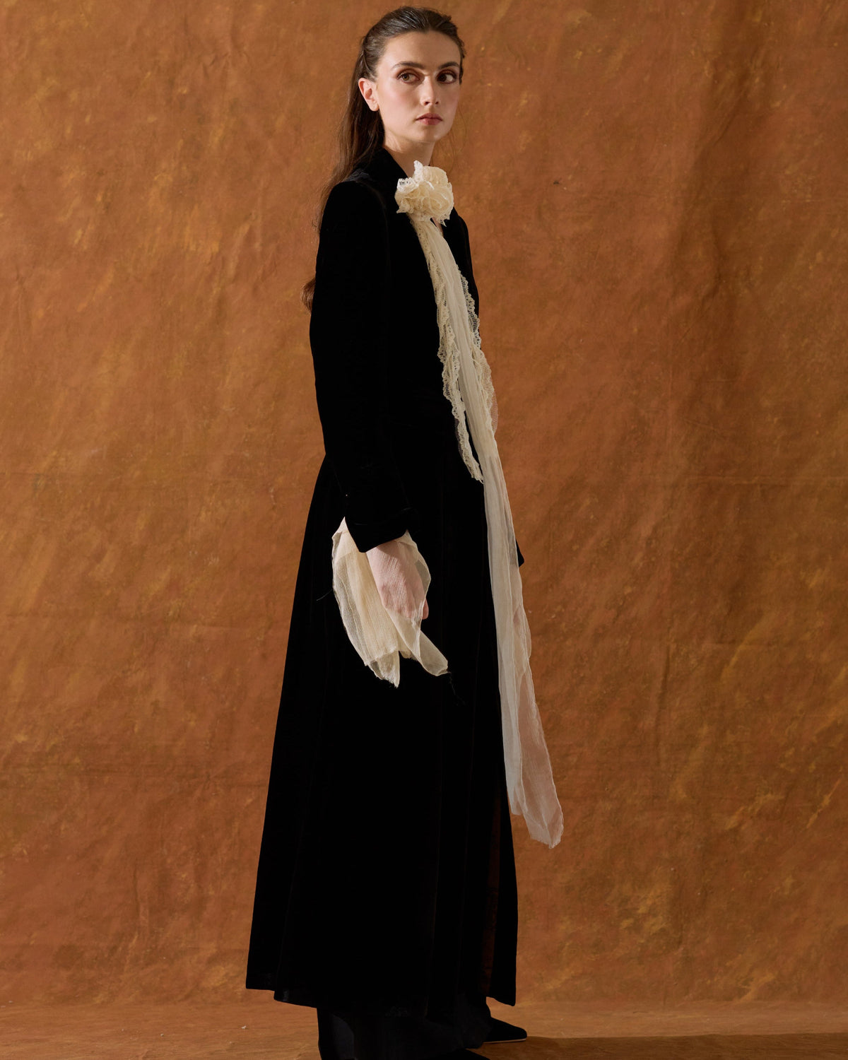 Side profile view of model displaying the drape and length of the black silk velvet Classic Coat for women by T.ba