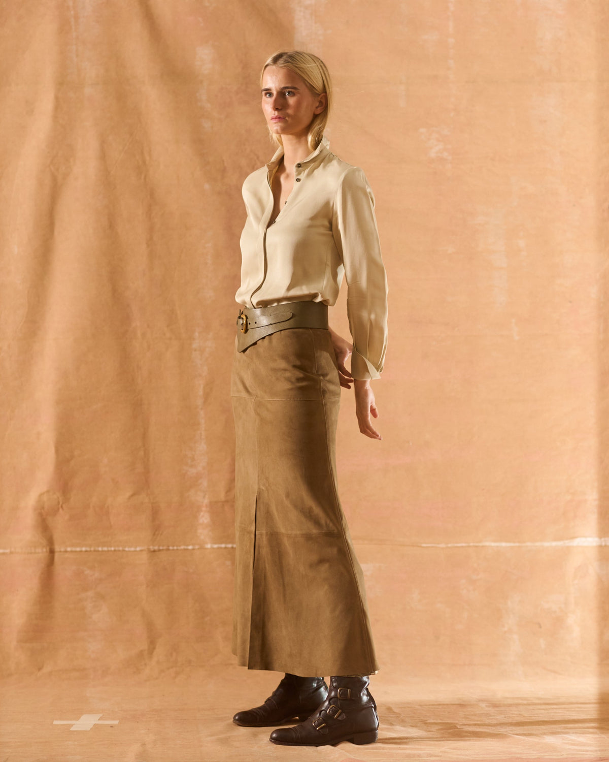 Full-length view of woman wearing beige Sharkskin Rania silk shirt paired with long suede skirt T.ba