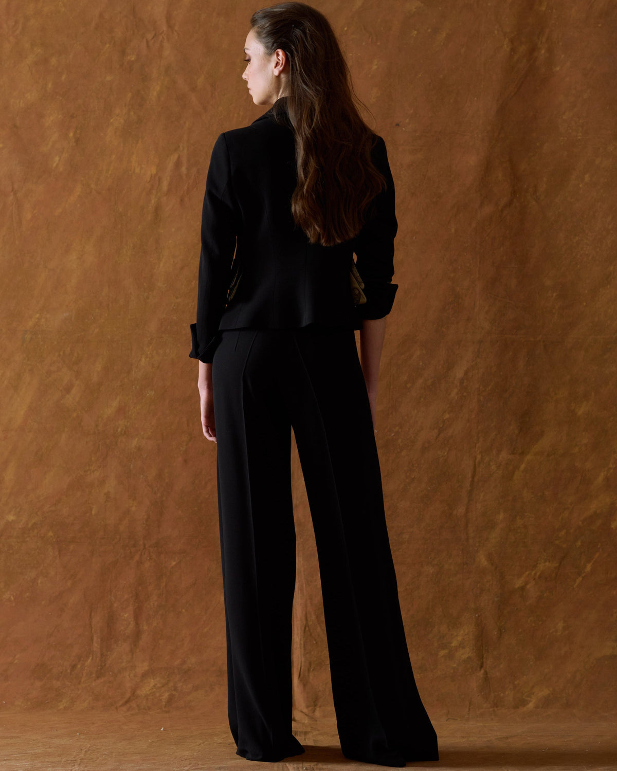 Three-quarter back view of model wearing the high-waisted Crepe Maxi Pants in black showing the elegant drape and wide fit for women by T.ba
