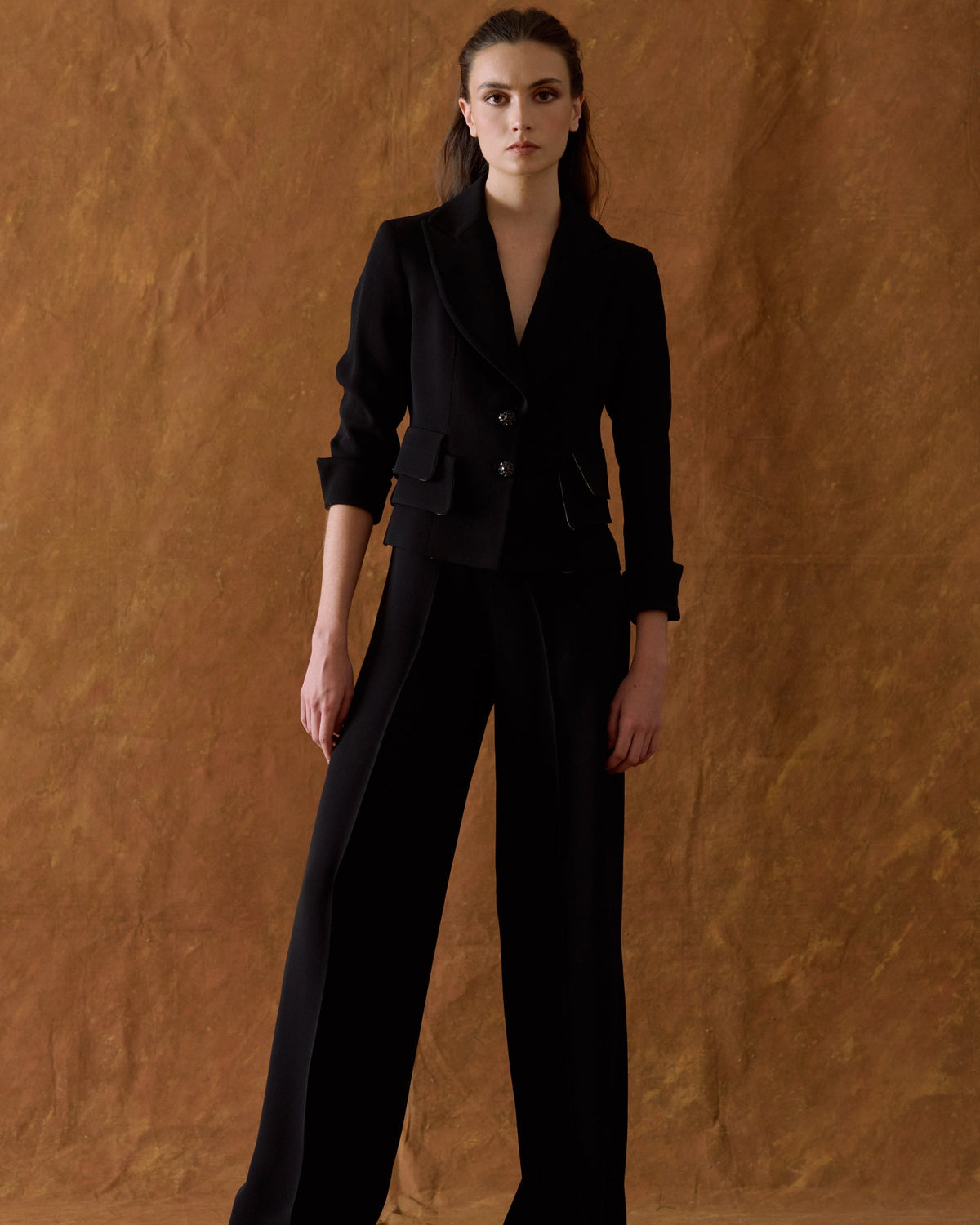 Full length front view of model wearing the wide-leg high-waisted Crepe Maxi Pants in black crepe fabric paired with a tailored blazer for women by T.ba