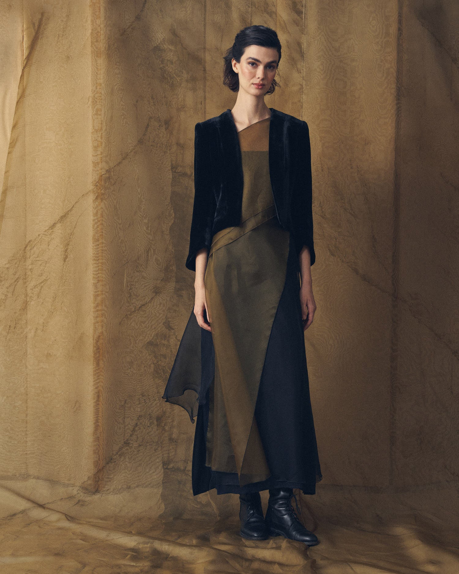 Full-length front view of model wearing the Daria silk velvet jacket in black with an asymmetric maxi dress by T.ba