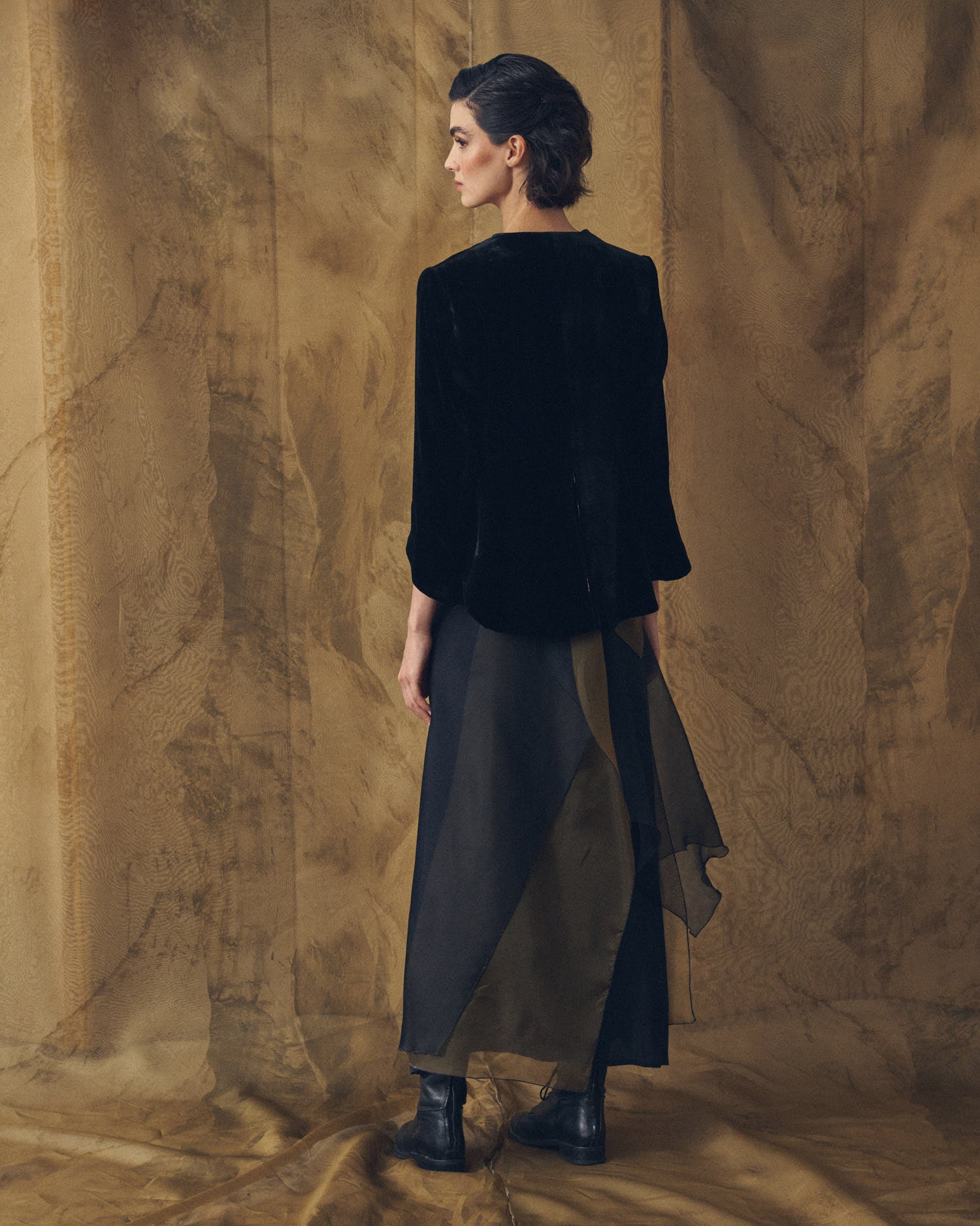 Back view of model wearing the Daria silk velvet jacket in black featuring a high-low hemline by T.ba