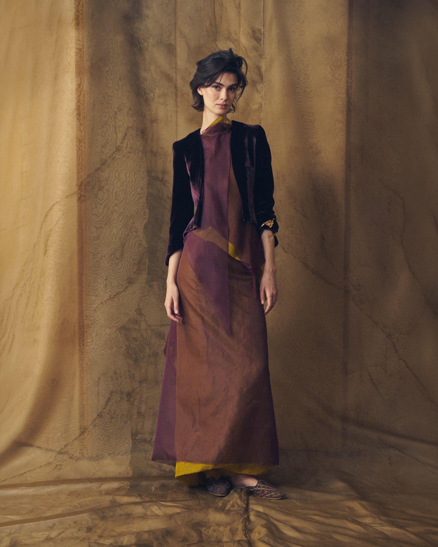 Full-length front view of model wearing the Daria silk velvet jacket in grape with a flowing maxi dress by T.ba