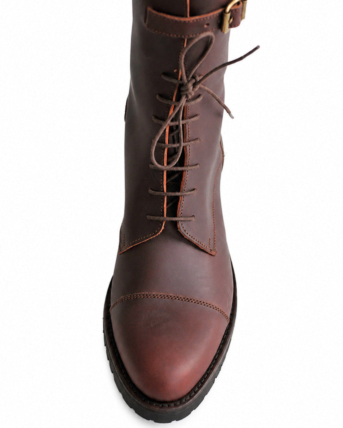 Close-up shot of rounded toe cap, front lacing, and brass buckle strap on dark brown leather boot T.ba