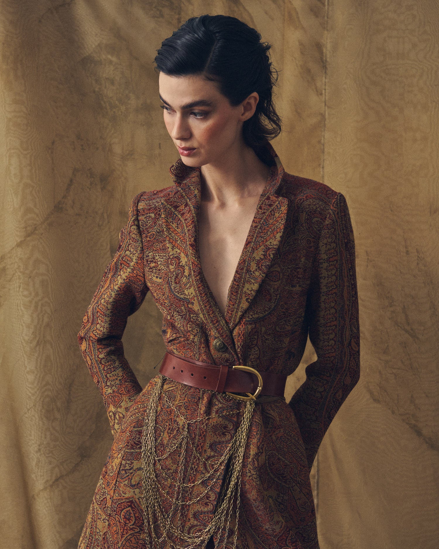 Three-quarter shot of model featuring the Duke Belt khaki leather belt defining the waist on a long printed jacket for women by T.ba