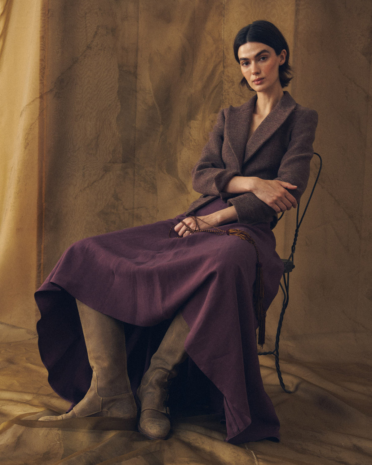 Model sitting on chair wearing beige suede Buckle Boots styled with plum midi skirt and wool jacket for women T.ba