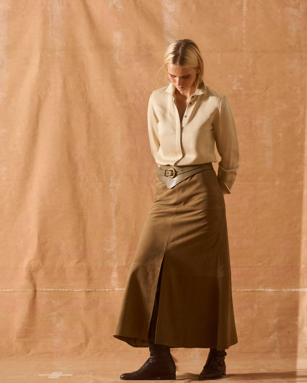 Full-length portrait of model posing in beige Sharkskin Rania silk shirt with leather belt and suede skirt T.ba