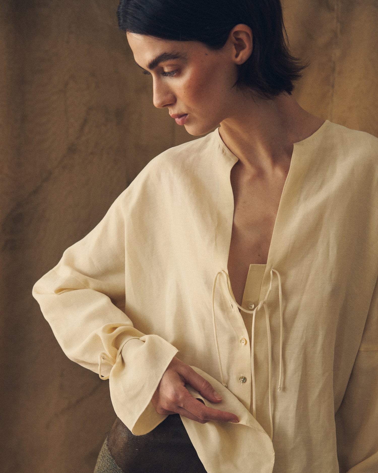 Close-up front view showing the soft texture, open V-neckline with ties, and button details of the natural cream Eloise Cupro Blouse for women T.ba