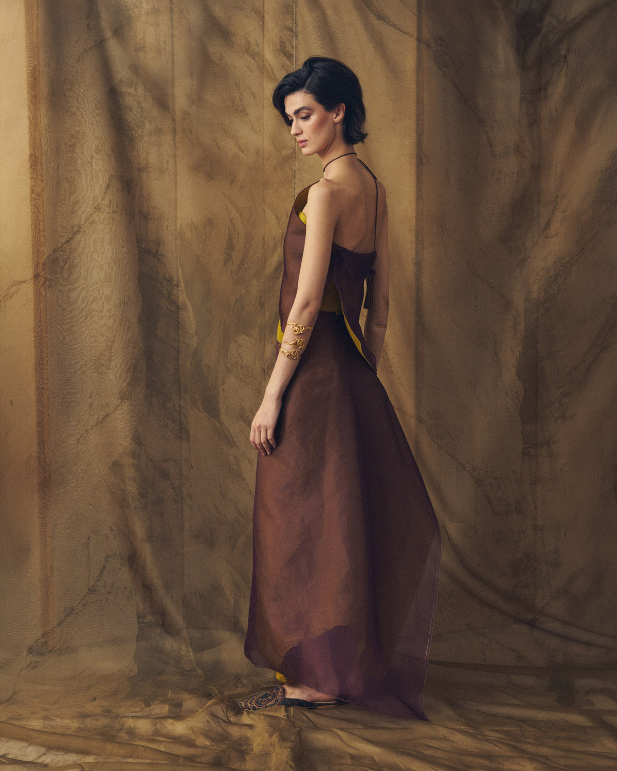 Side profile view of the Fiore top in aubergine and arbequina silk organza showing side drape and tassel tie neck by T.ba