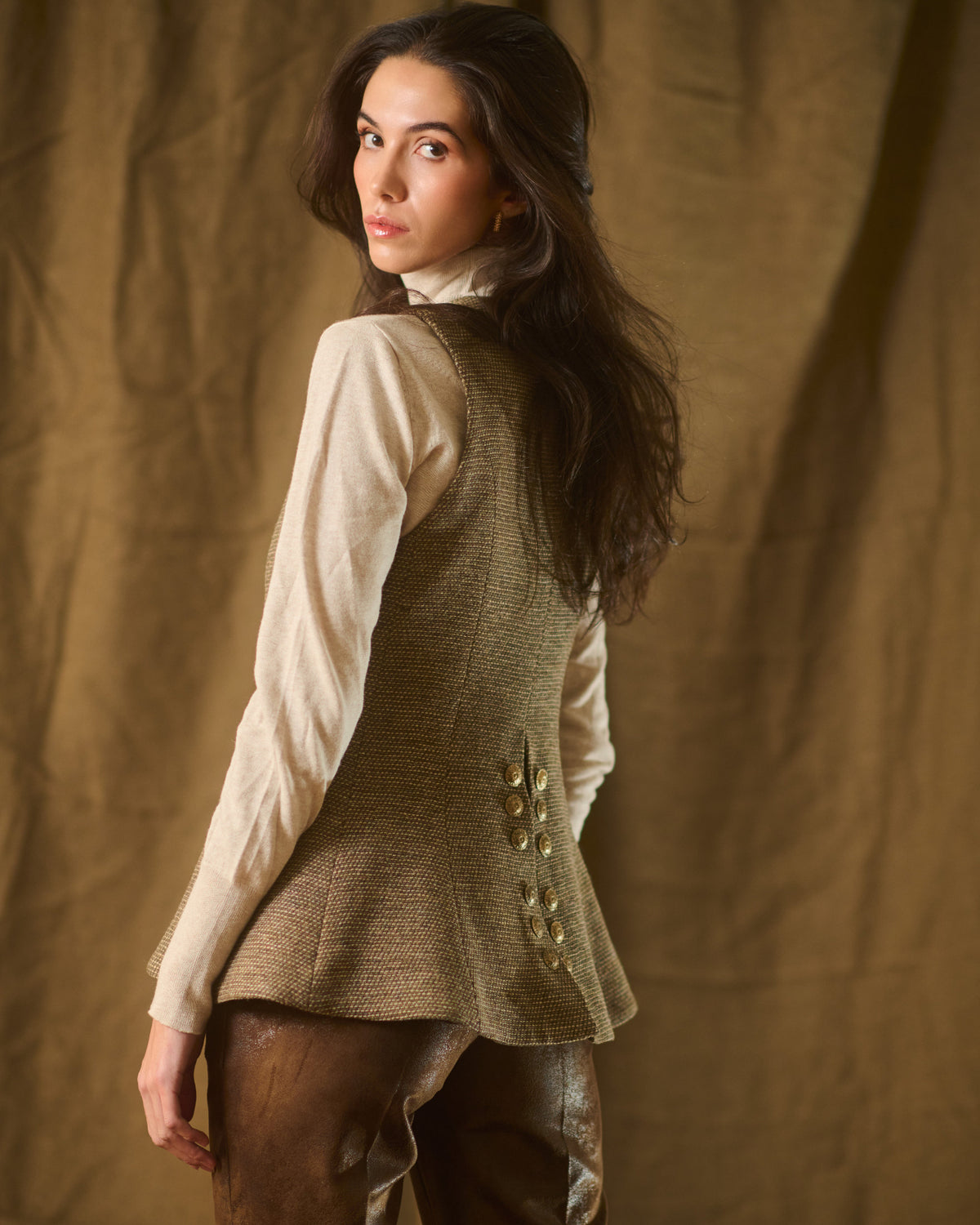 Over-the-shoulder side view of woman wearing flared taupe tweed knit Baltea vest T.ba