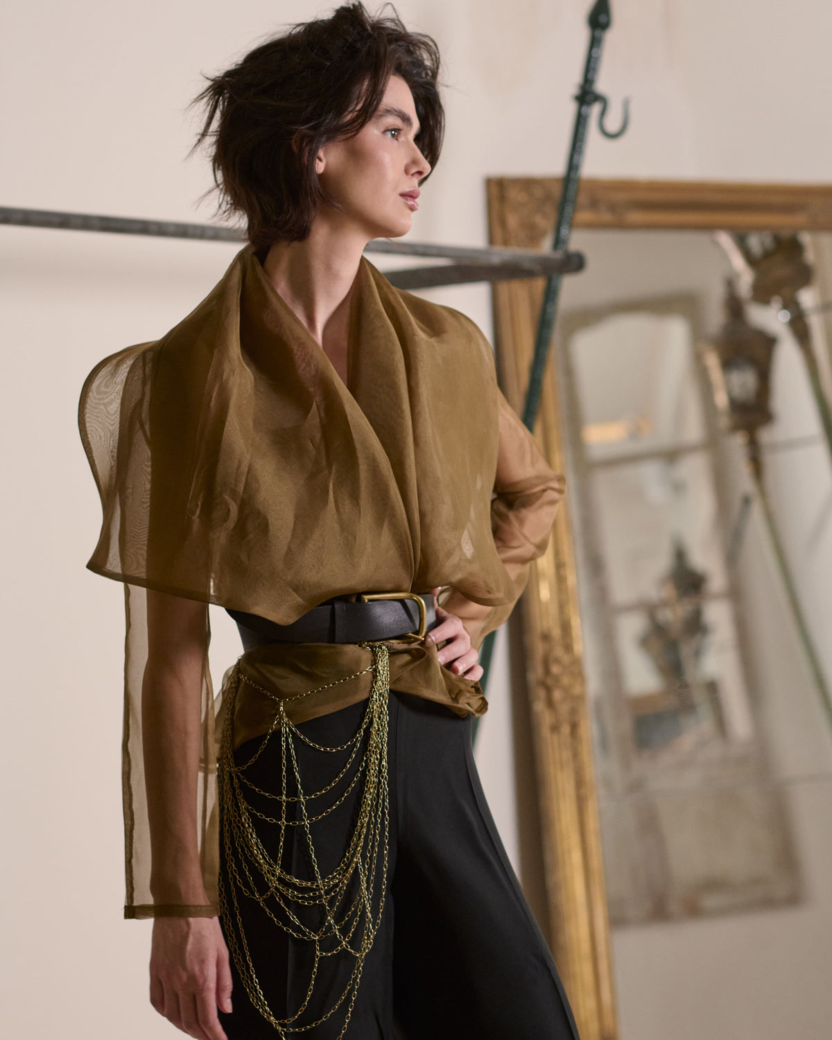Front angle view of model wearing sheer Organza Alina jacket in toffee with wide belt and chain accessory T.ba