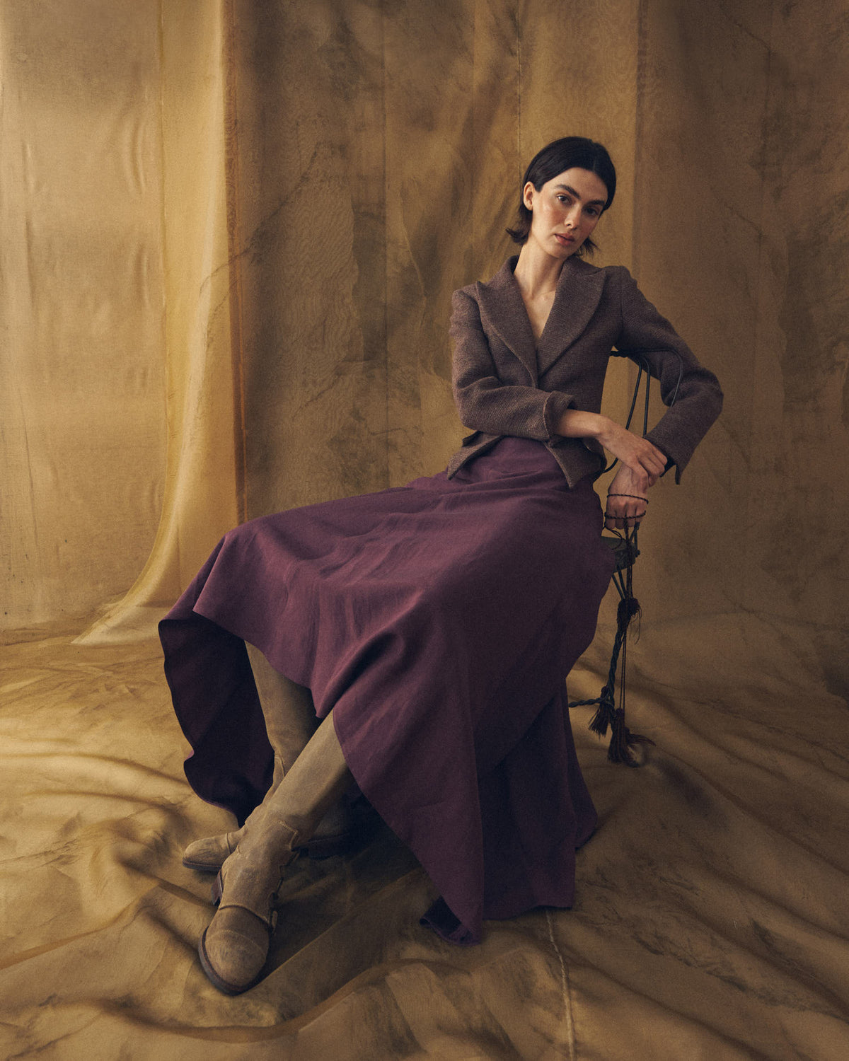 Full-length portrait of model wearing high beige suede Buckle Boots with purple skirt and tailored jacket T.ba