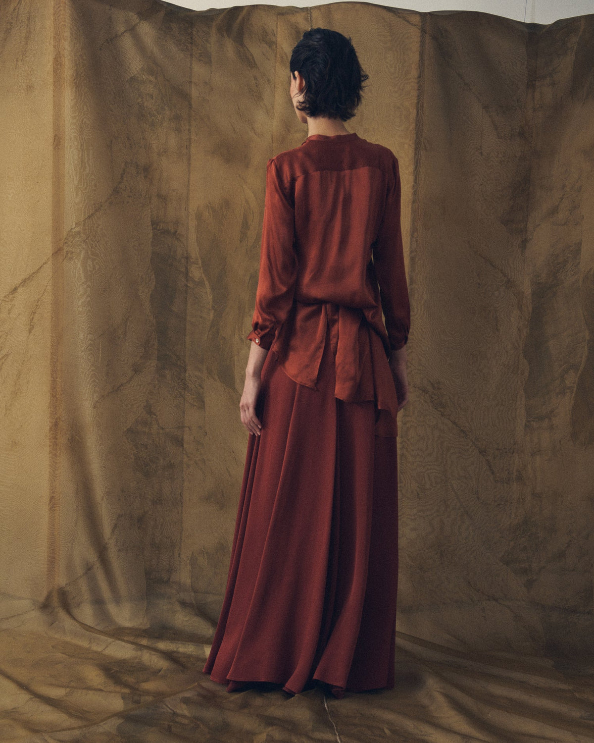Back view of the Georgette Mao shirt in fluid champagne red fabric with a draped silhouette for women T.ba