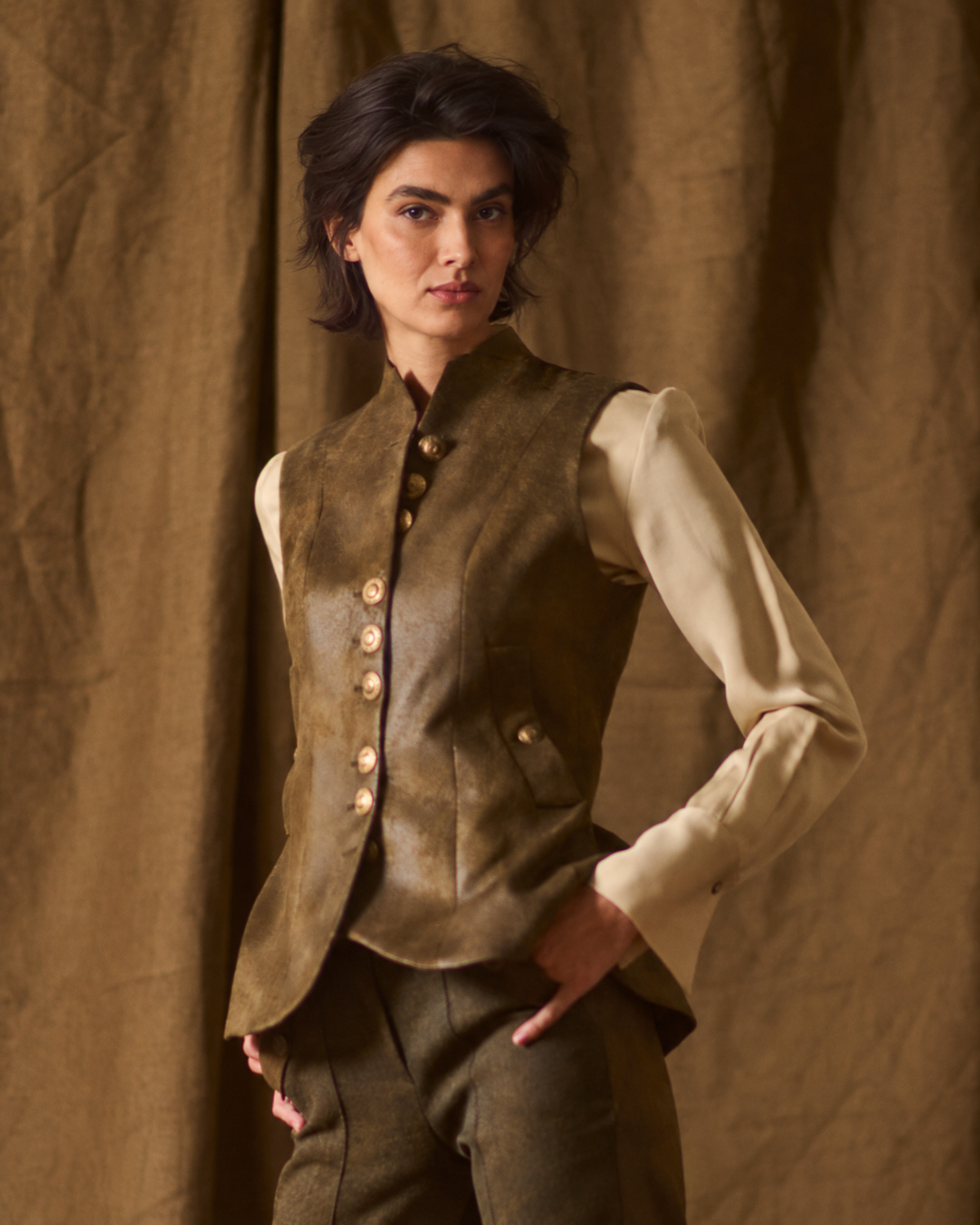 Medium front view of model wearing the fitted Gnu Baltea Vest in khaki suede leather with gold buttons for women by T.ba