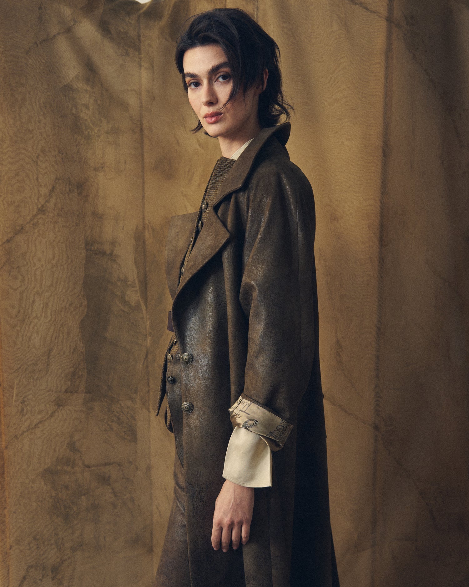 Close-up side view of the T.ba Gnu Biella coat in khaki waxed linen, highlighting the detailed turned-back patterned silk cuff.