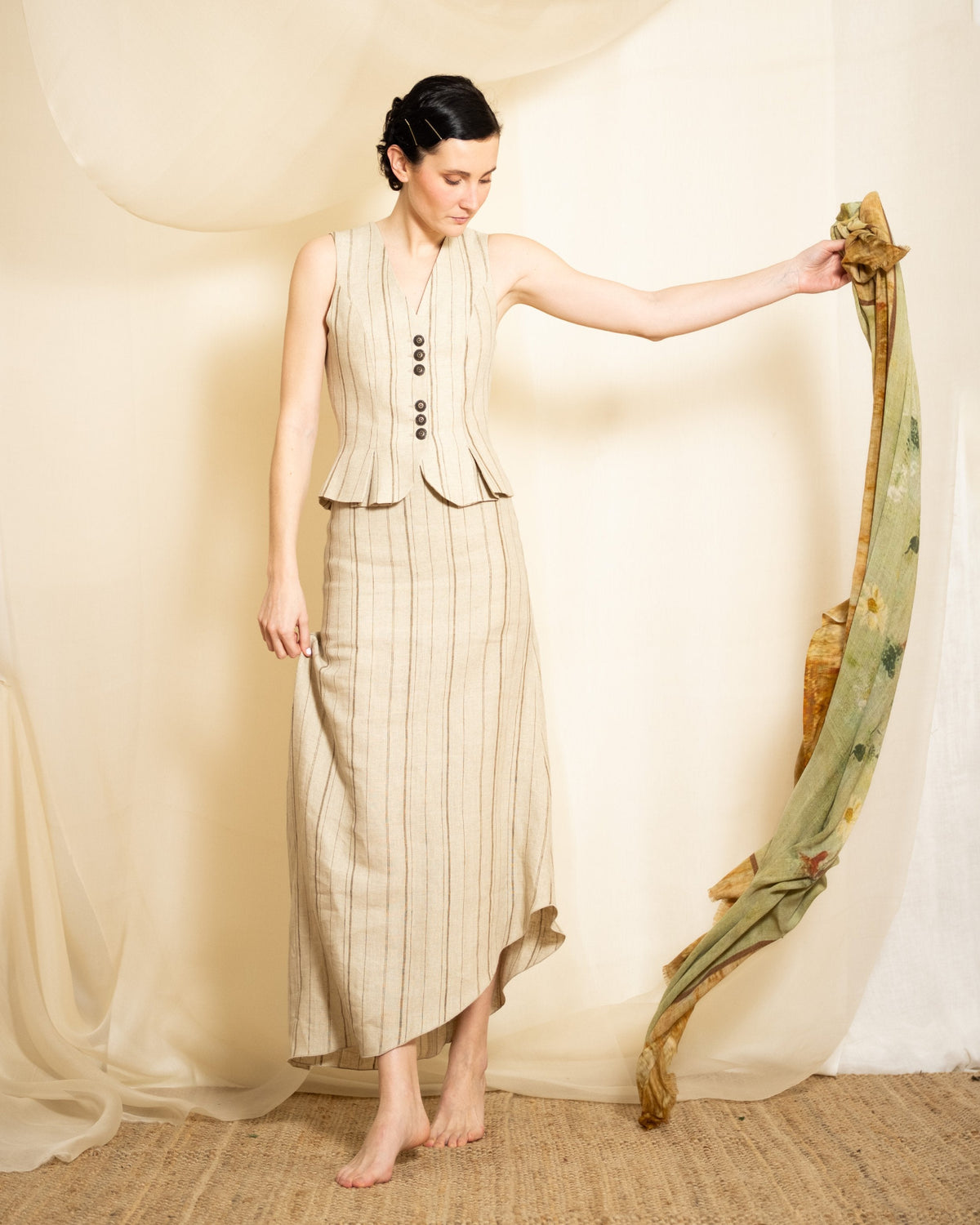 Model holding flowing Greta printed wool shawl showing green and earth tones landscape pattern for women T.ba