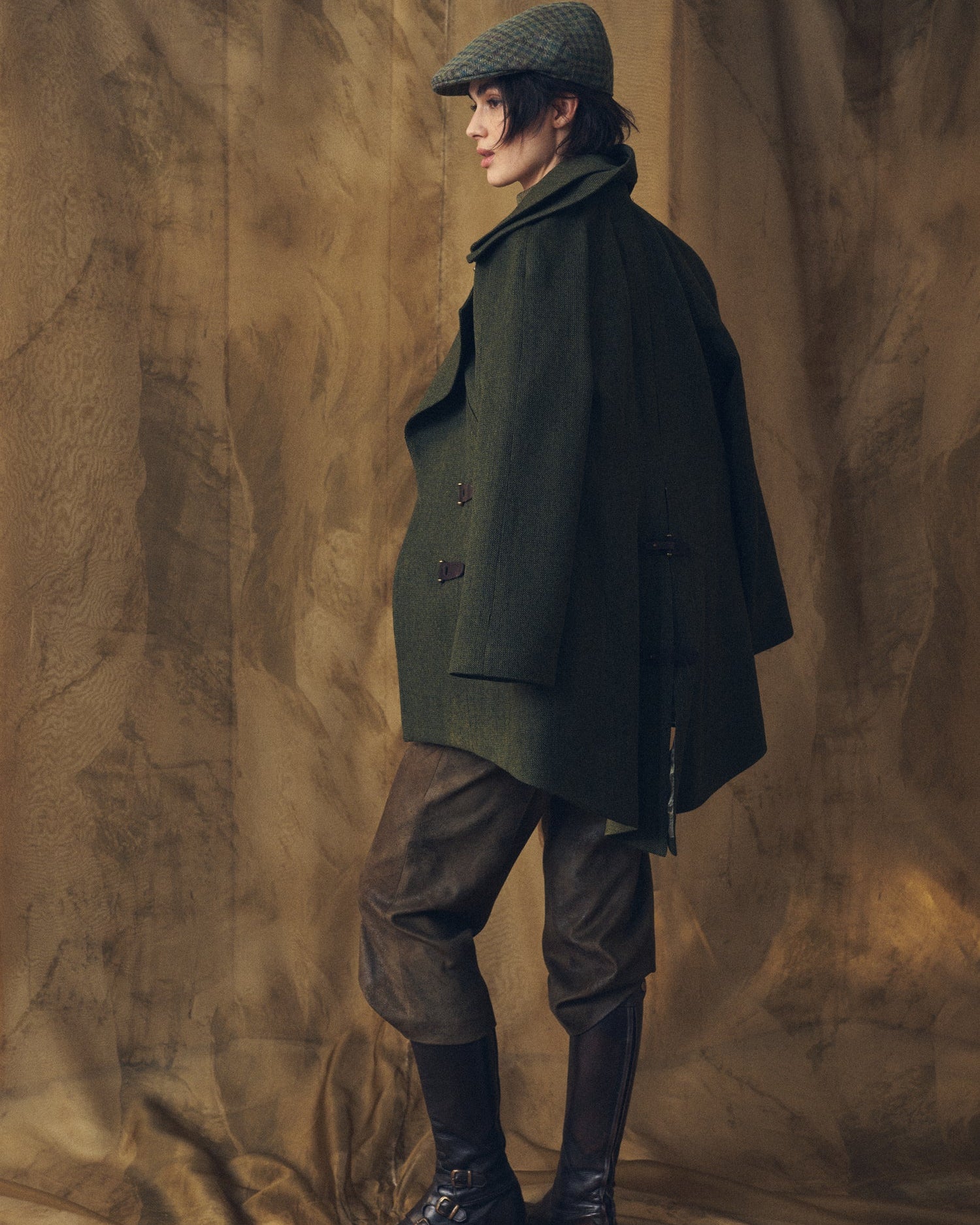 Side profile view of the Jerez Biella Field Coat in hunting green wool tweed showing the cape-style silhouette and lapel collar for women by T.ba.