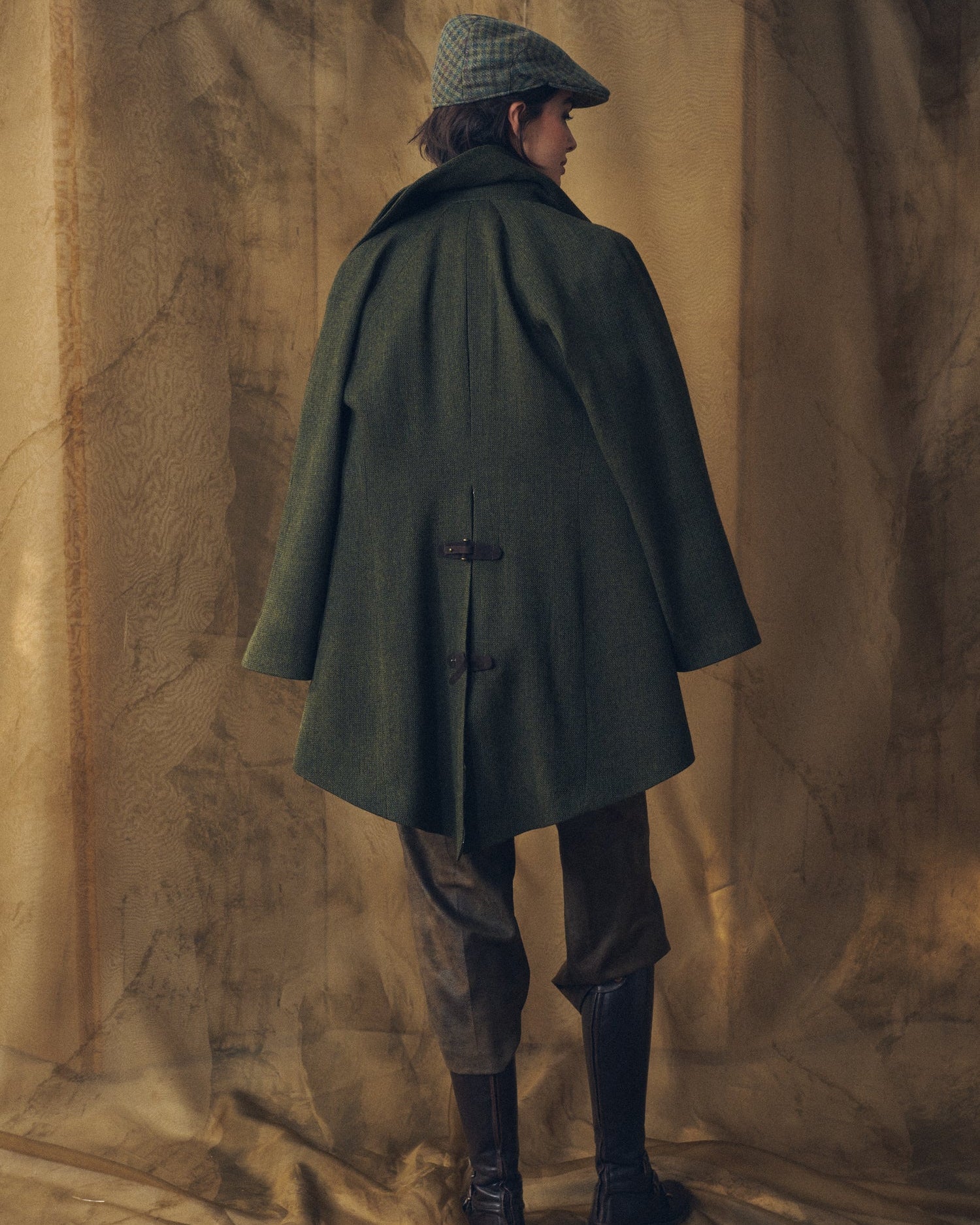 Back view of the Jerez Biella Field Coat in green wool tweed showing the pleated back structure and strap details for women by T.ba.