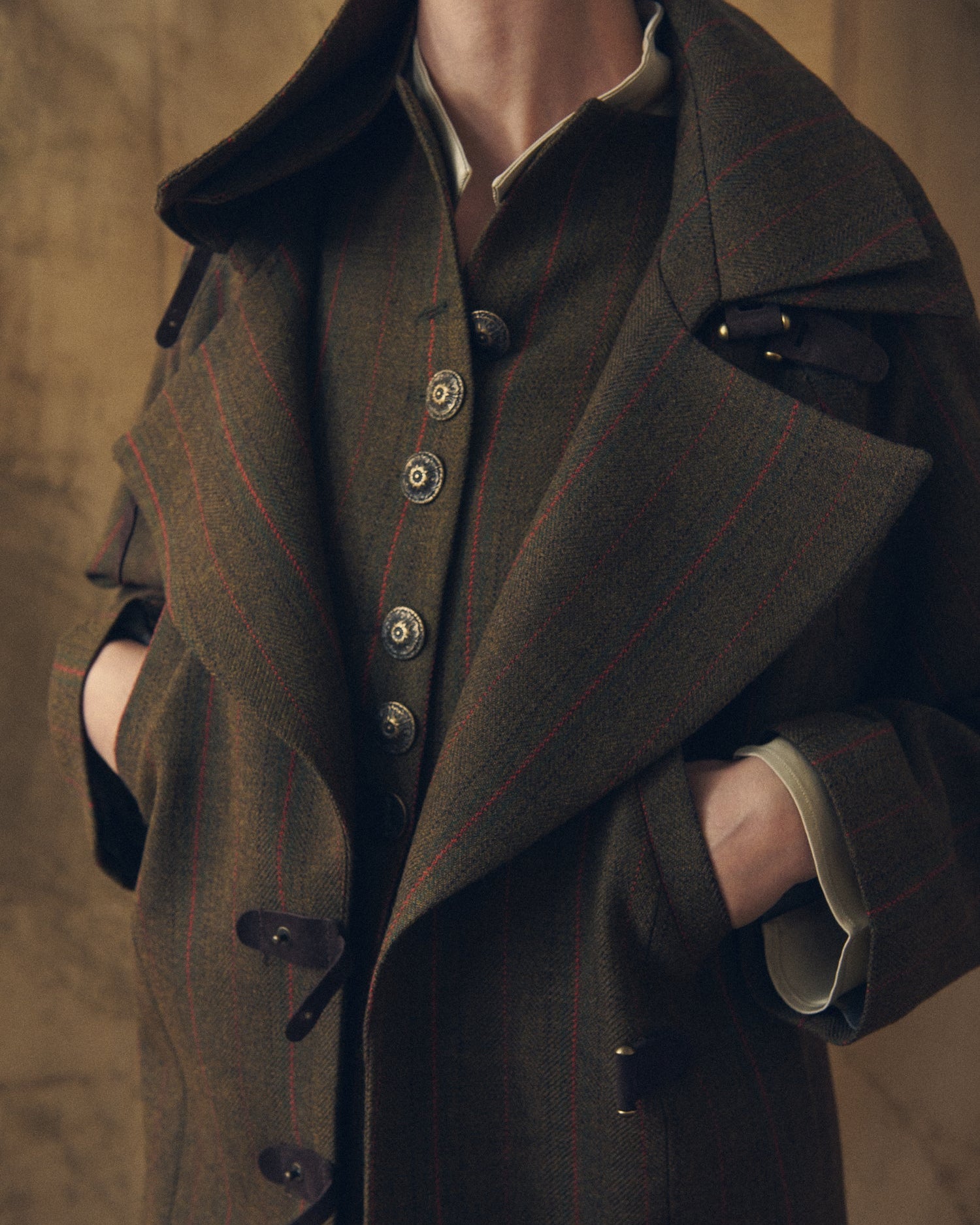 Close-up front view of the Jerez Biella Field Coat in khaki wool with red pinstripes showing vintage metallic buttons and wide lapels by T.ba.