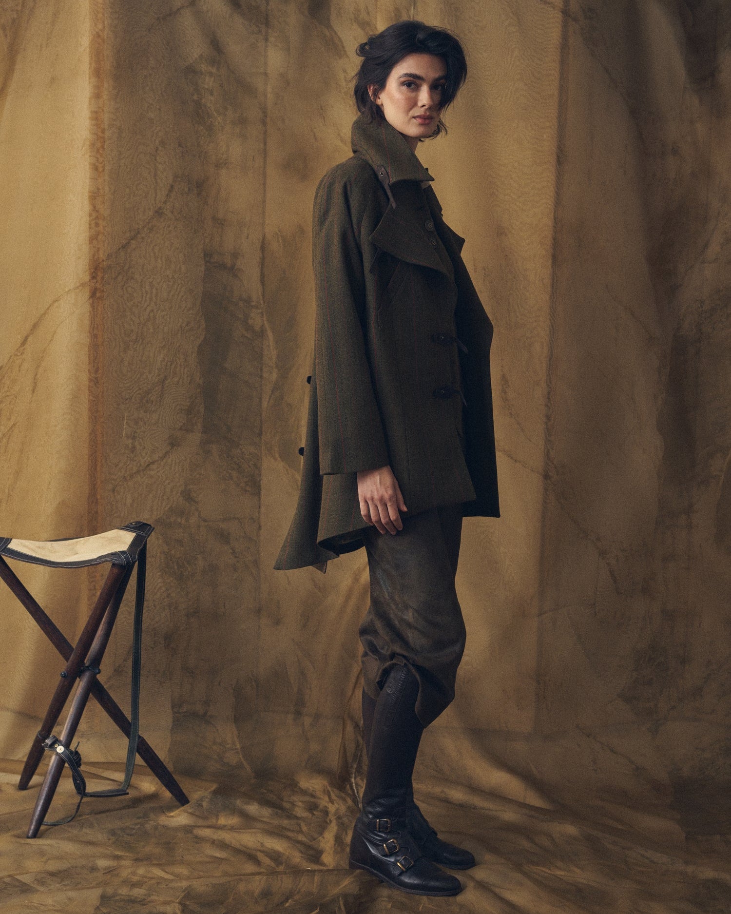 Side profile view of the Jerez Biella Field Coat in khaki wool tweed showing the asymmetrical hem and cape collar for women by T.ba.