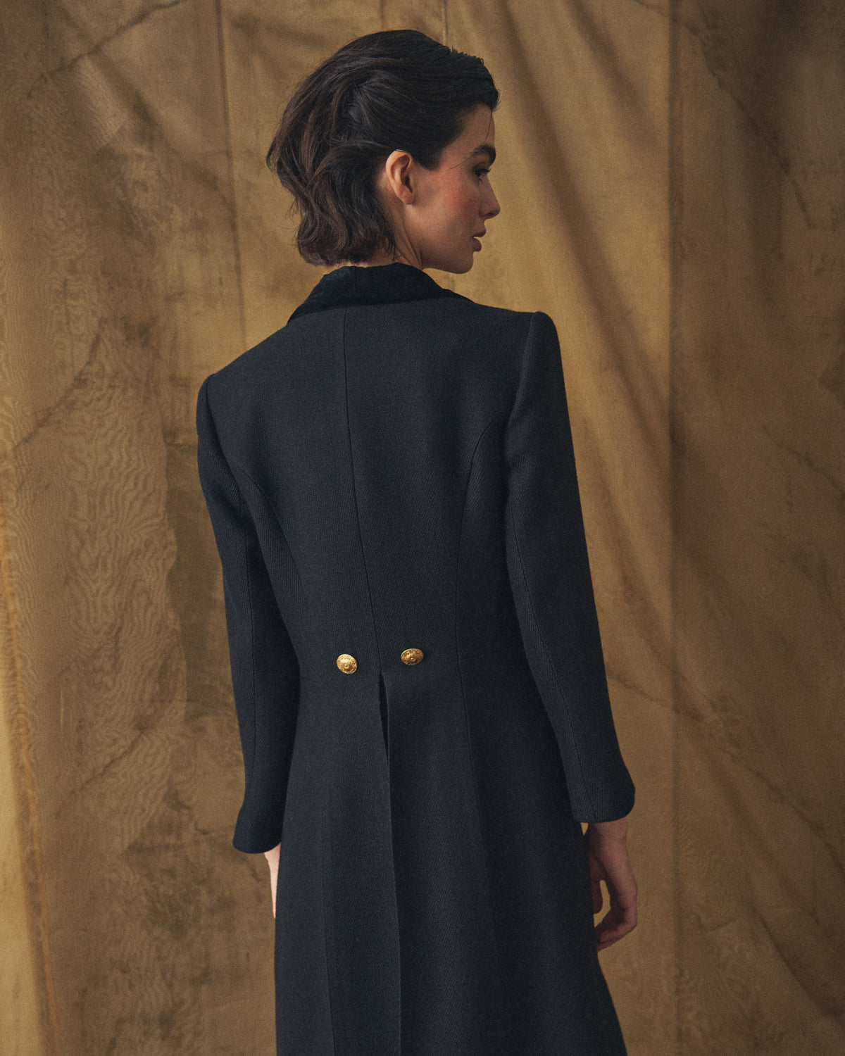 Medium rear shot showing the tailored back structure and velvet collar of the Jerez Lancelot Combi Coat in black wool for women by T.ba