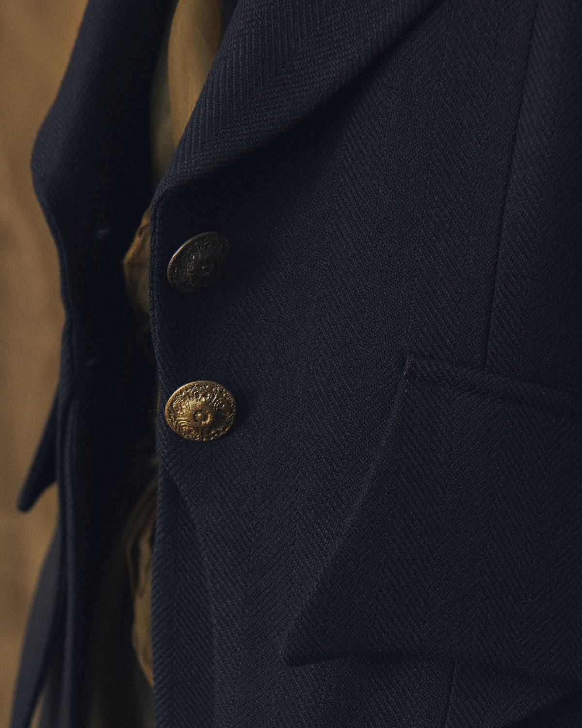 Close-up shot highlighting the fine twill wool texture and ornamental antique gold buttons of the Jerez Verdi Coat in black for women by T.ba
