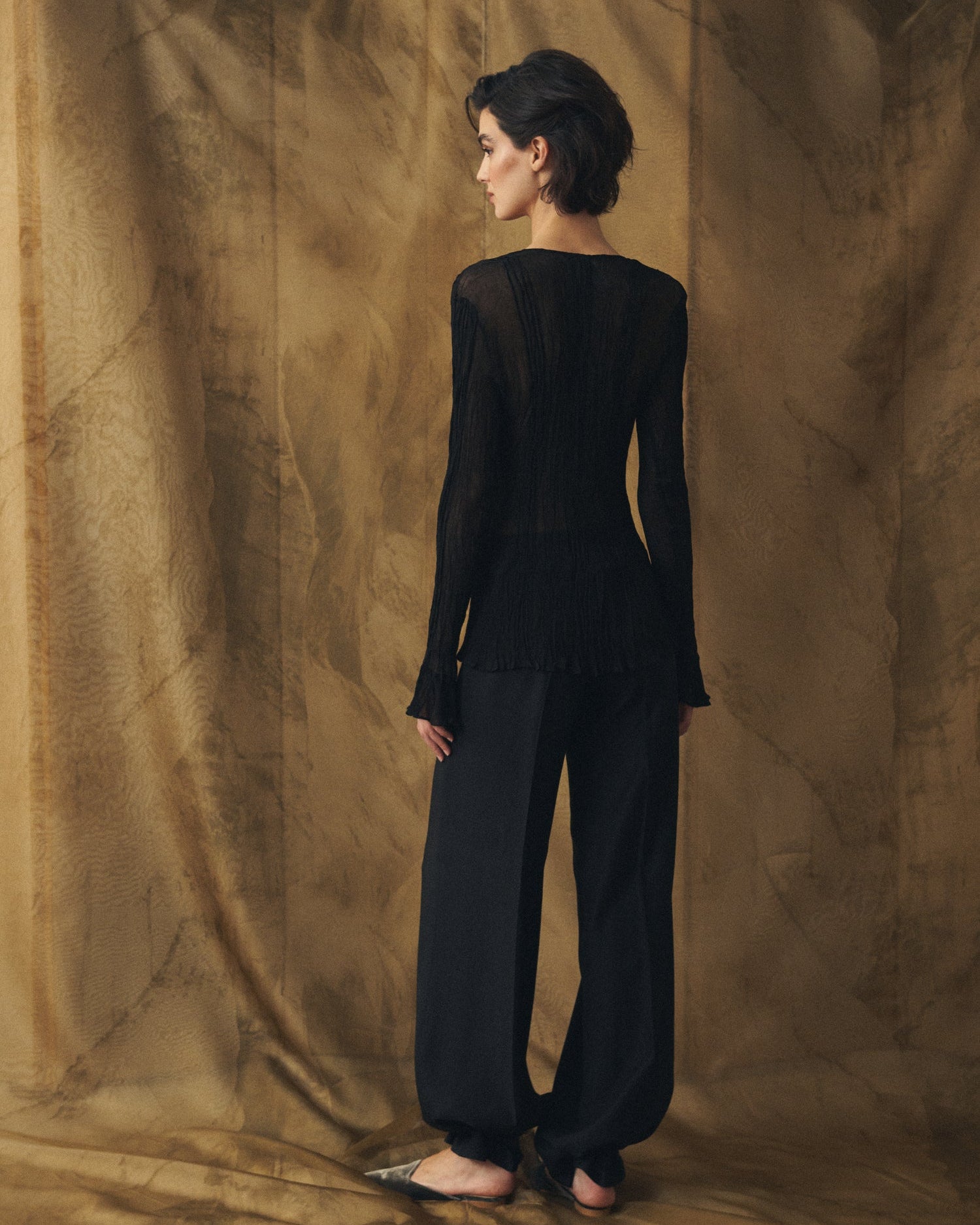 Back view of the Lizzie pleated black chiffon blouse with a fitted silhouette for women T.ba