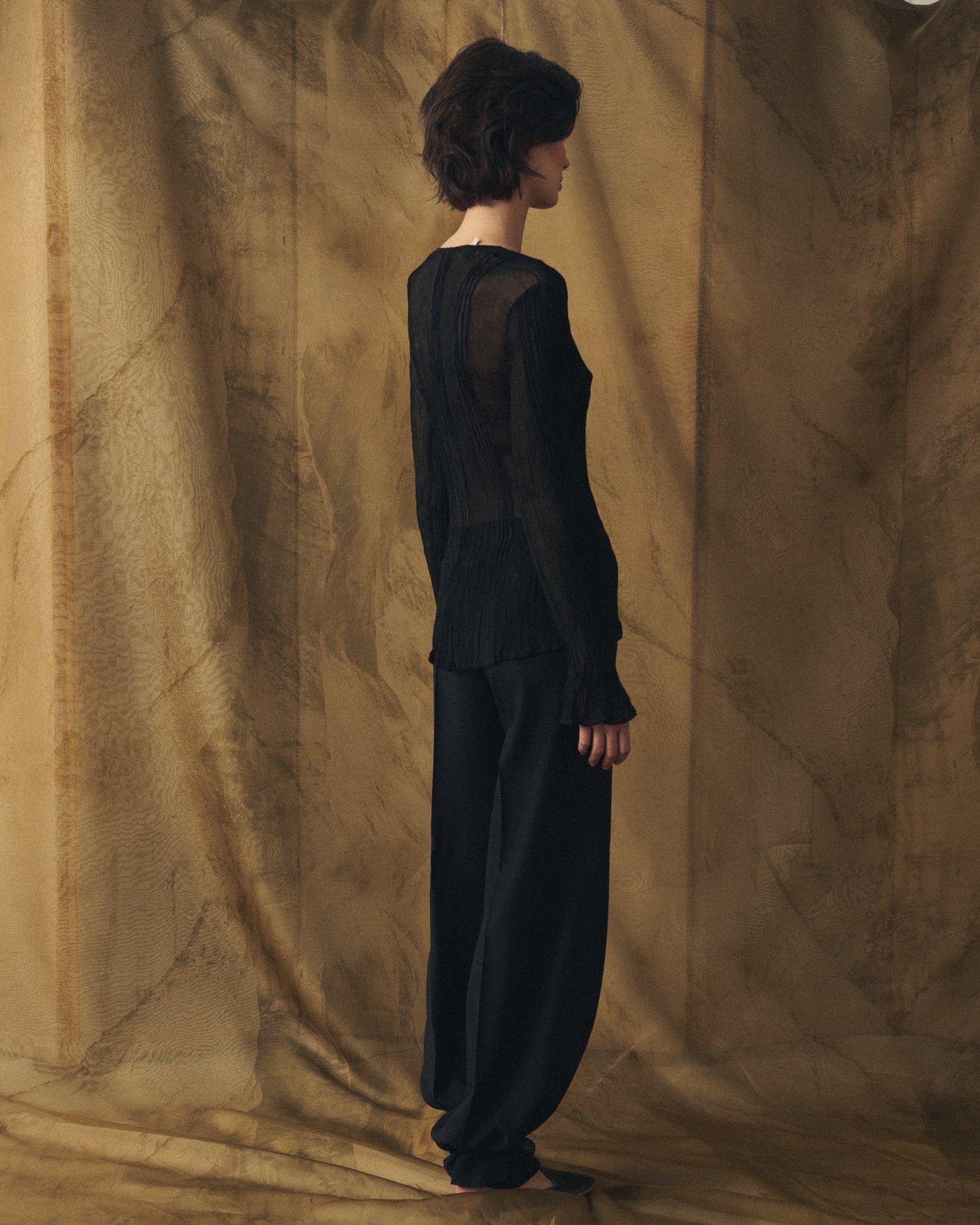 Side view of the Lizzie sheer black chiffon blouse featuring subtle flared cuffs for women T.ba