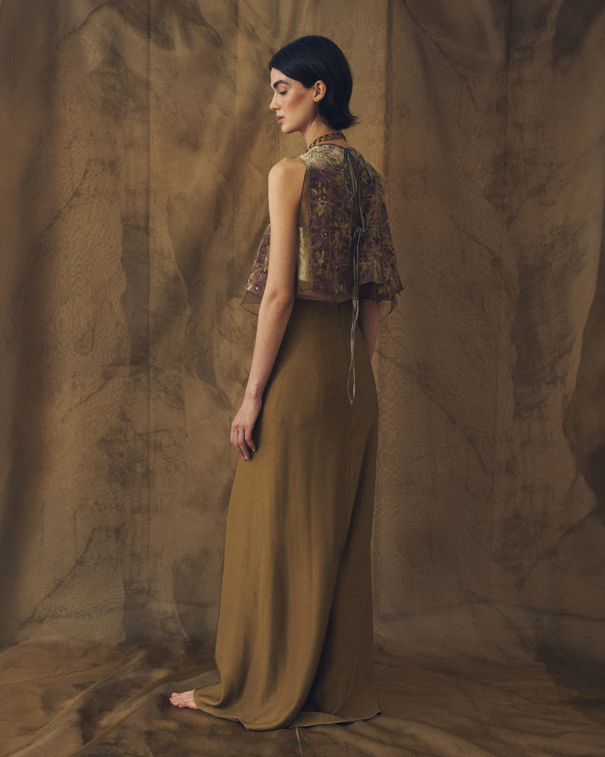 Three-quarter back studio view of model wearing the fluid Noor maxi sharkskin skirt in khaki by T.ba