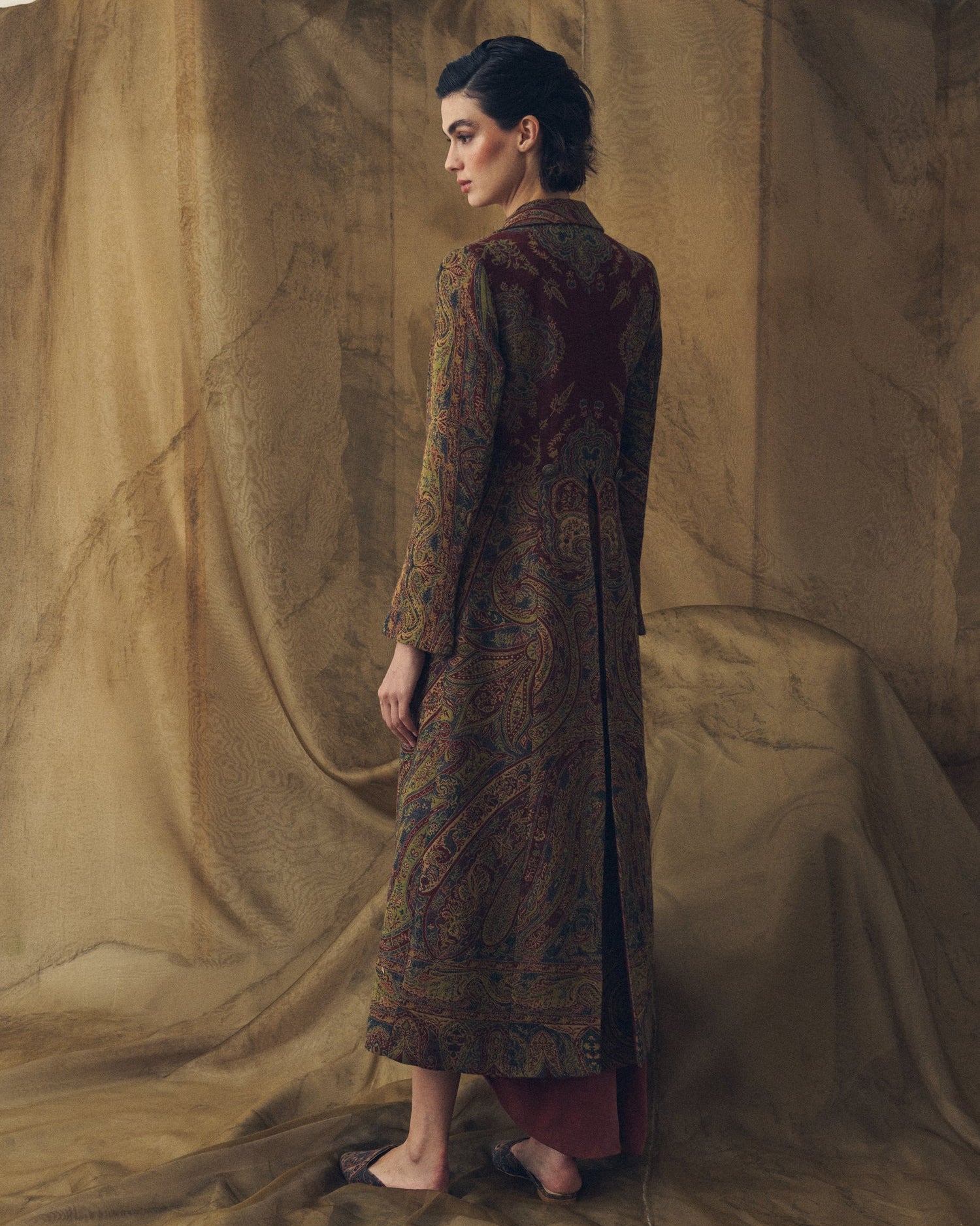 Three-quarter rear view of women's Jacquard Lancelot long coat showing back vent and paisley pattern by T.ba