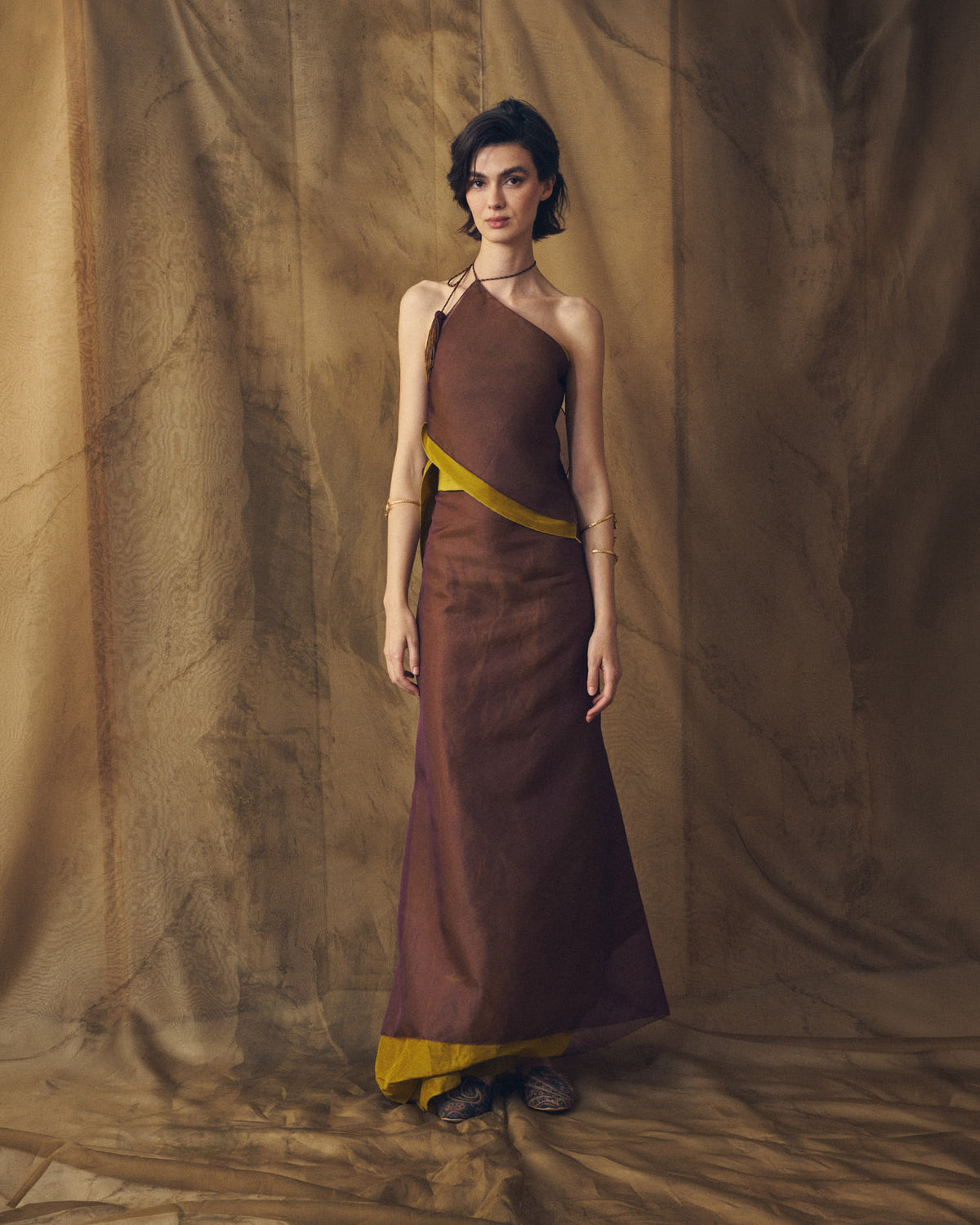 Full-length front studio view of model wearing the asymmetrical Panarea top in aubergine silk organza paired with long skirt by T.ba